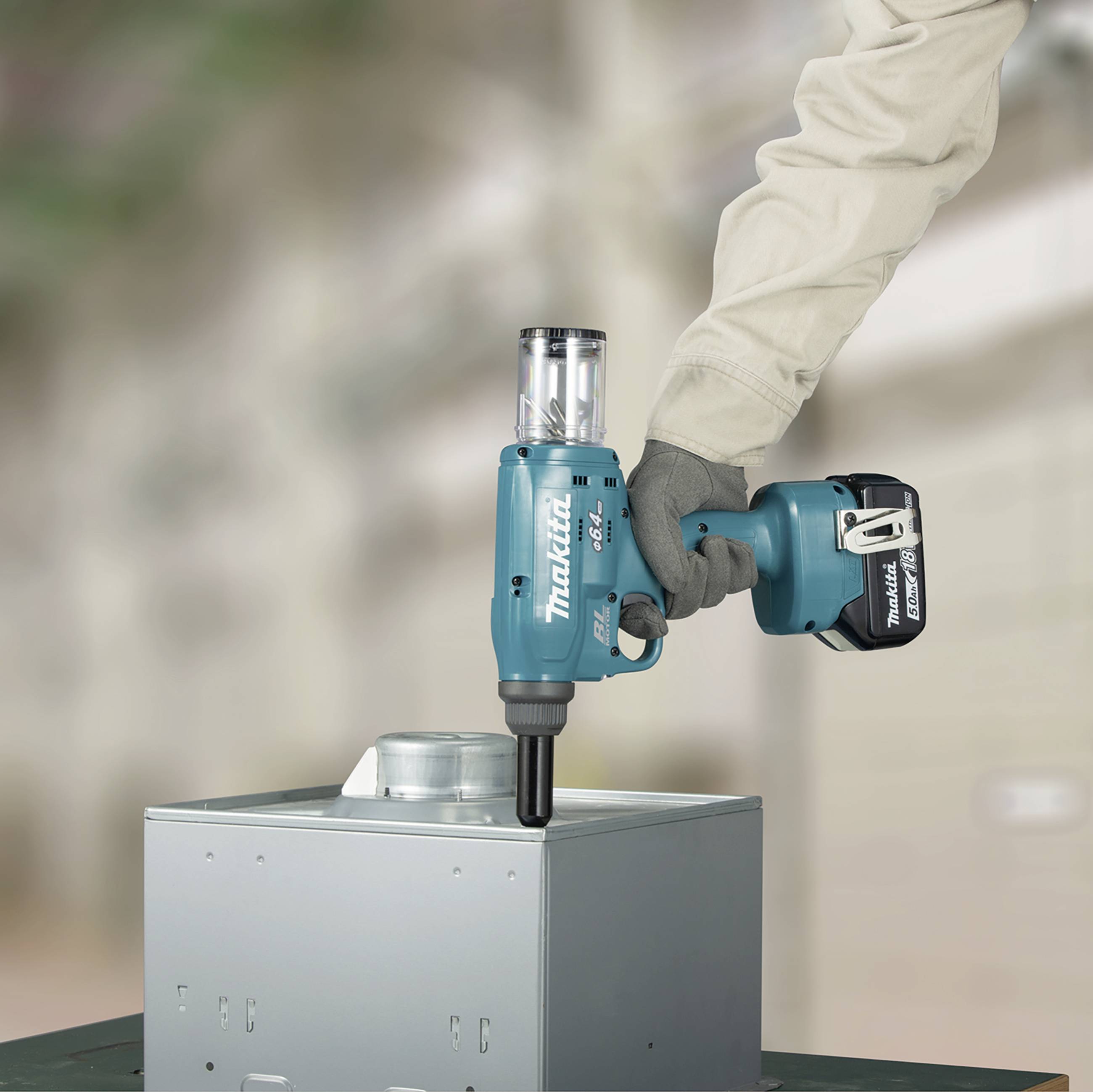 Een boormachine wordt gebruikt om gaten te maken in een metalen object. De persoon draagt werkhandschoenen.