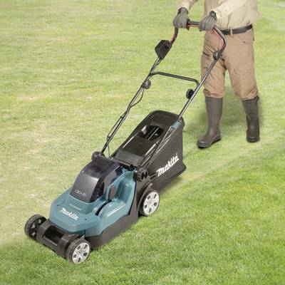 Een persoon maait een gazon met een elektrische grasmaaier van Makita. De persoon draagt tuinhandschoenen en rubberen laarzen.