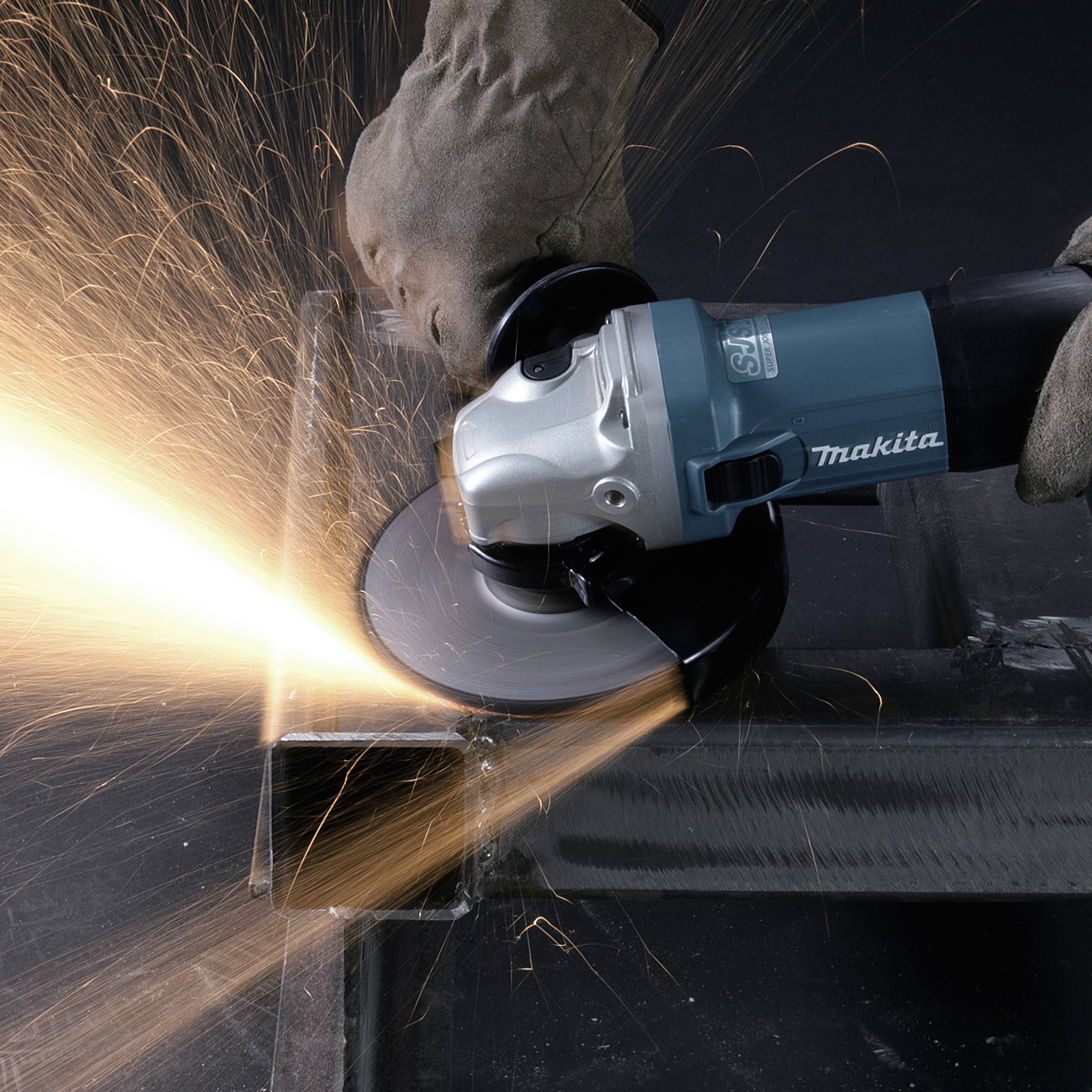 Een persoon werkt met een elektrische haakse slijper aan een metalen stuk. Vonken spatten van de slijpschijf.