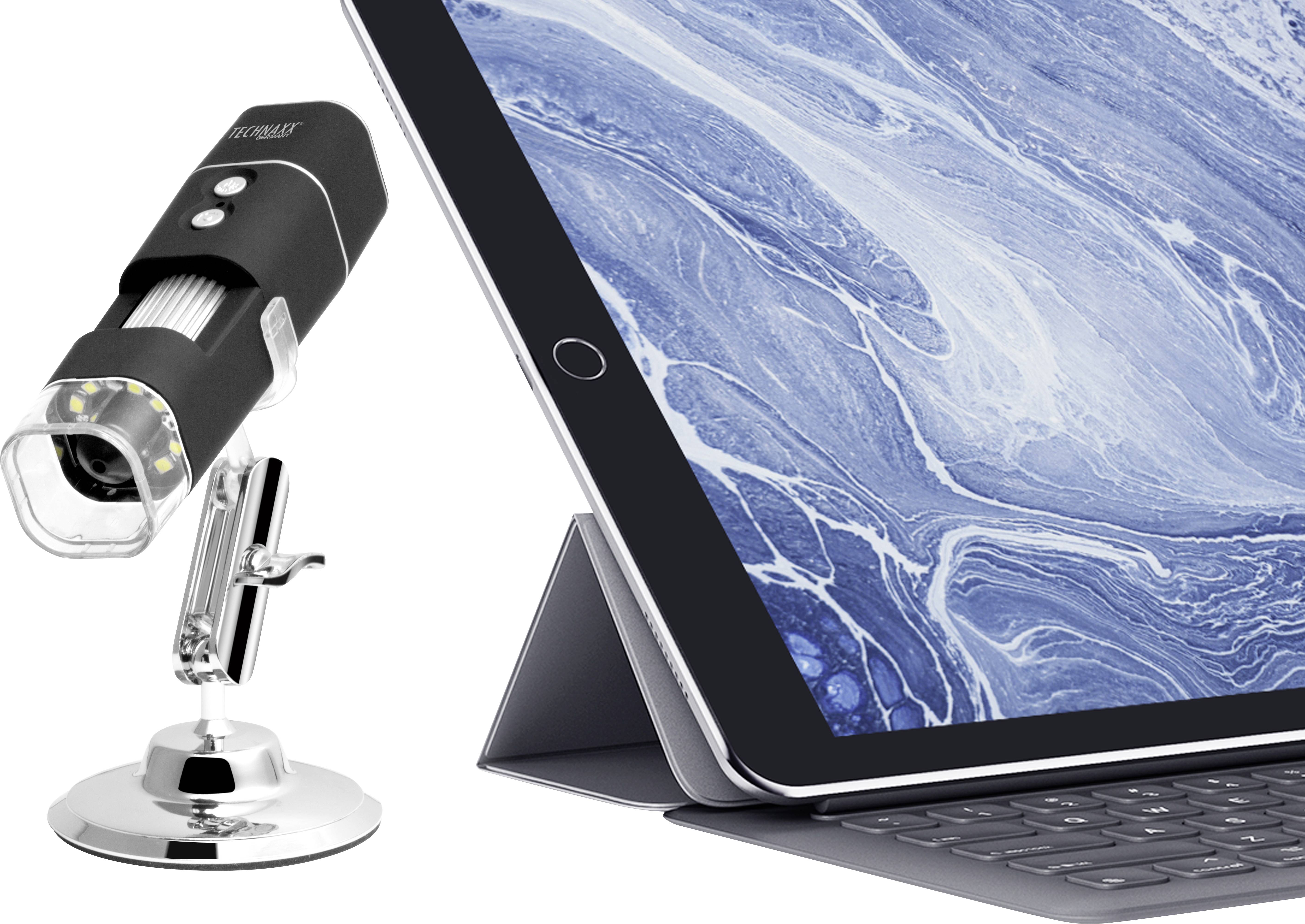 Een digitale microscoop naast een tablet met toetsenbord dat een close-up toont van een blauw, gemarmerd patroon.