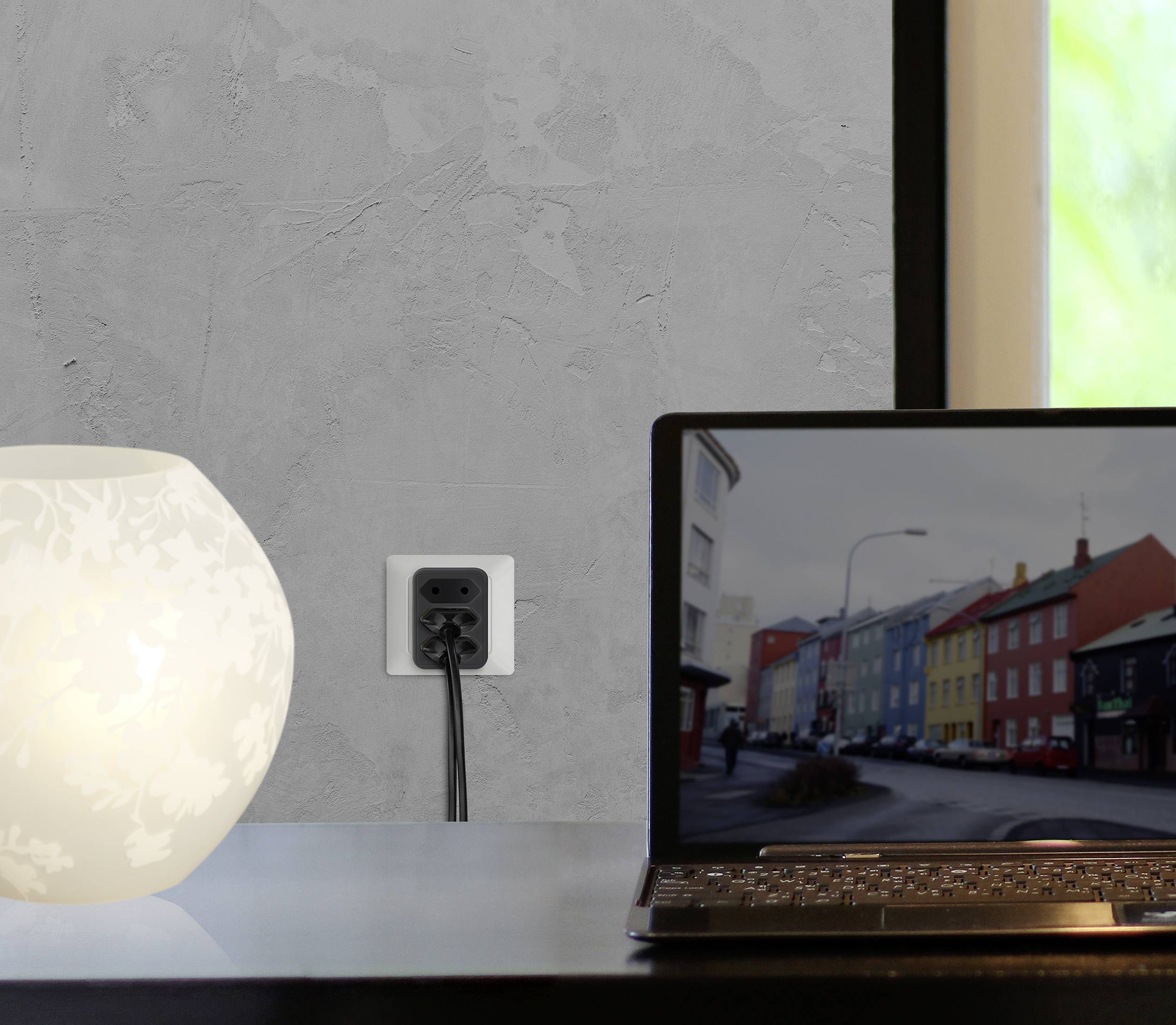 Een laptop toont een straatbeeld met kleurrijke gebouwen. Ernaast staat een ingeschakelde, decoratieve lamp op een tafel.
