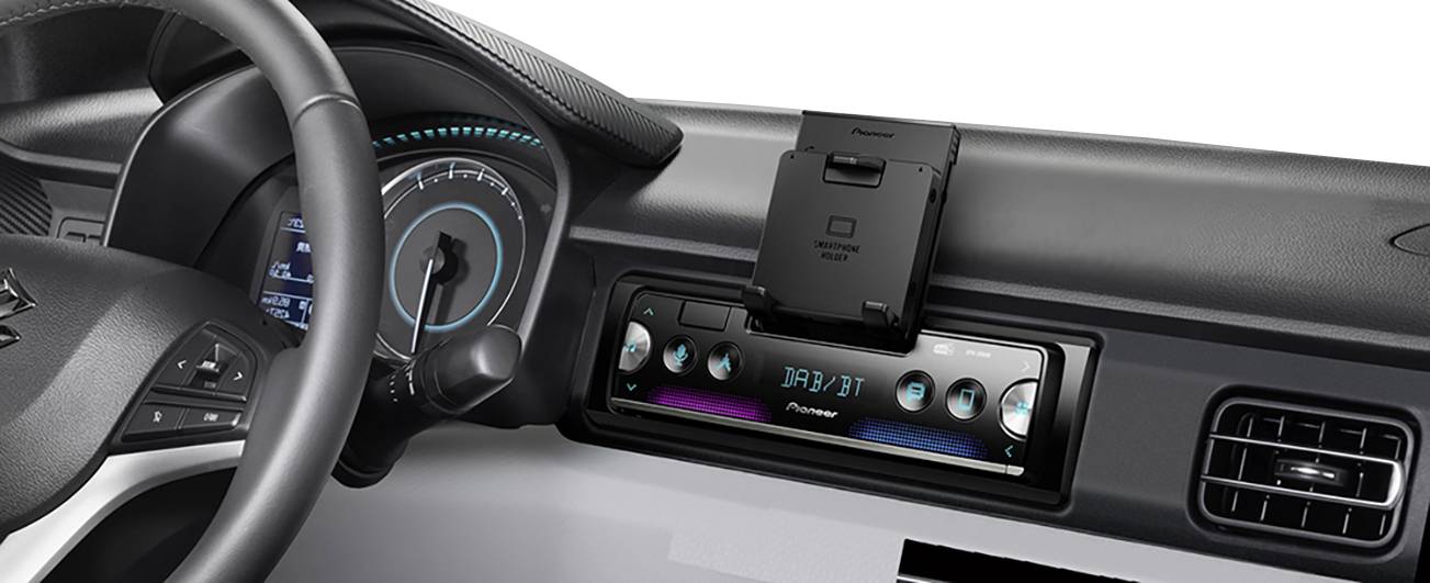 Autoradiodisplay in een auto met verlichte bedieningselementen en digitale weergave van 'FM 87.9'. Links daarvan het stuurwiel.