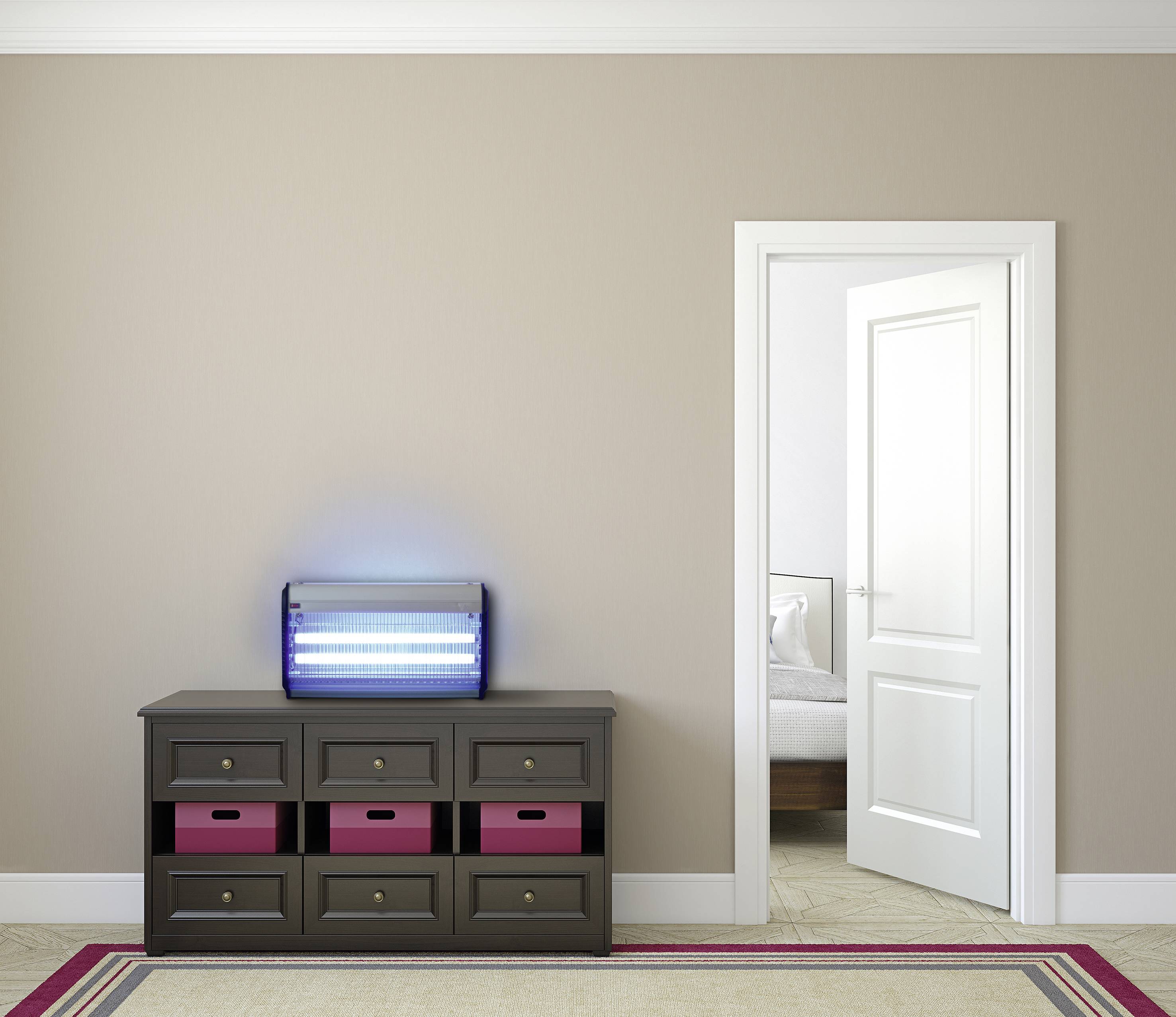 Een modern ingericht vertrek met een open deur naar een slaapkamer. Op de ladekast staat een oplichtende UV-lamp.