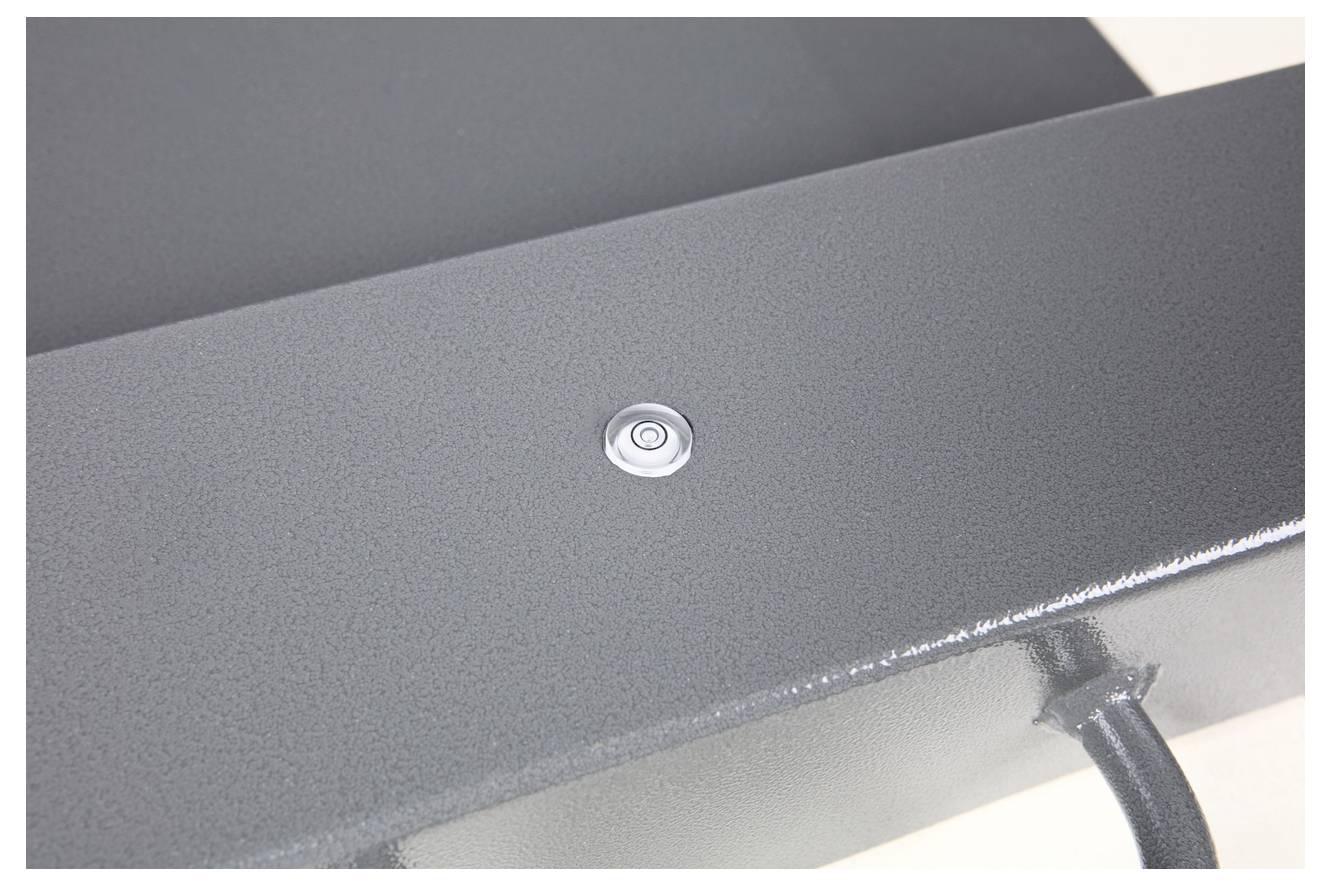 Een grijze metalen tafel met een kleine, ronde knop in het midden. Een kabel loopt van de rechterbenedenhoek van de tafel.