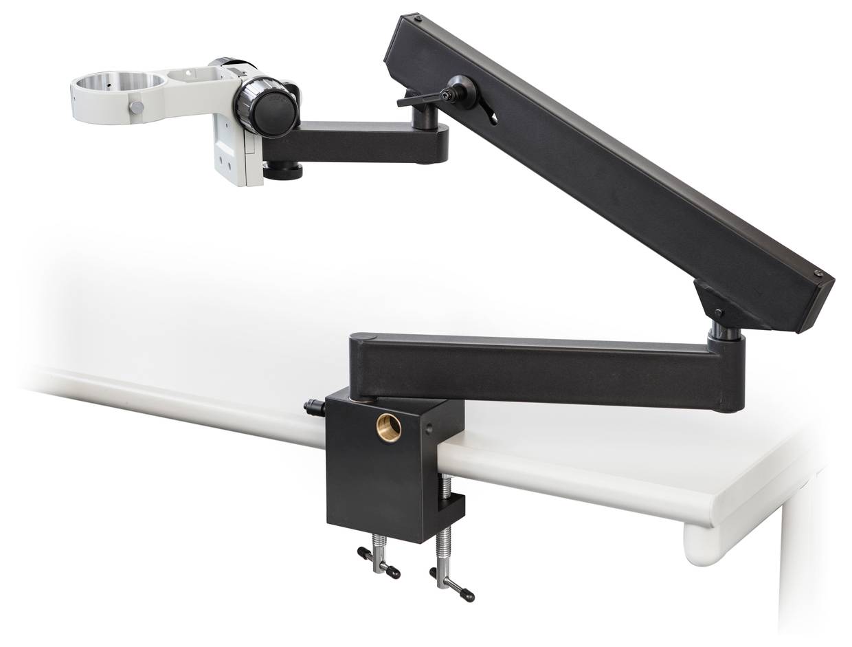 Een zwarte, verstelbare monitorarm is bevestigd aan een wit bureau. De arm beschikt over meerdere scharnieren voor flexibele positionering.