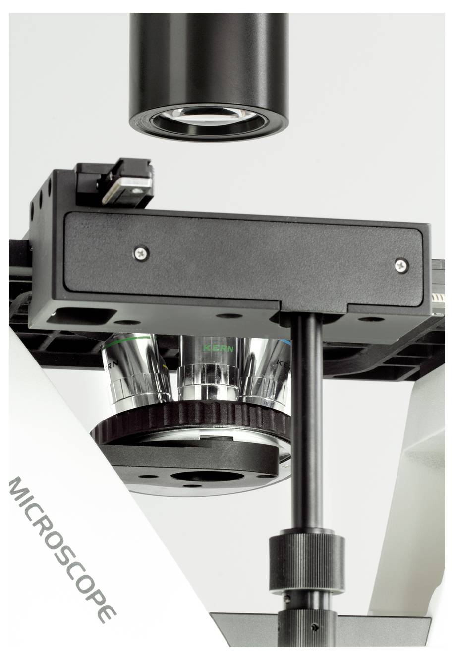 Microscoop close-up, gericht op de objectieflens en het objecttafel, mogelijk gebruikt voor wetenschappelijke analyse of onderwijs.