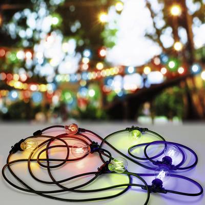 Een kleurrijke lichtsnoer ligt op een tafel, wazig licht op de achtergrond creëert een feestelijke en gezellige sfeer.