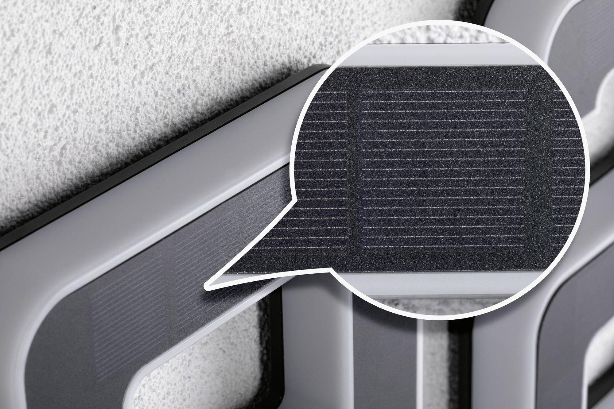 Close-up van een zonnepaneel geïntegreerd in een gebouwoppervlak, uitgelicht door een vergrootglas.