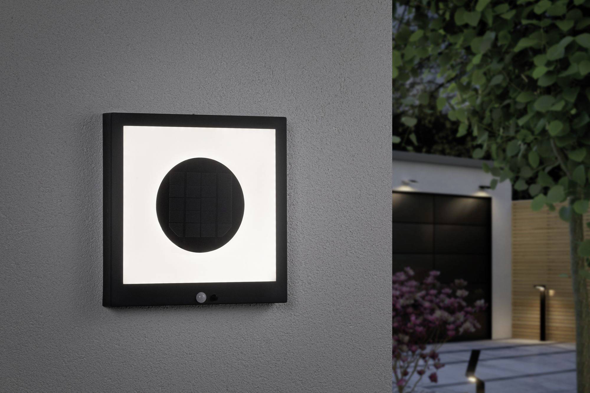 Buitenwandlamp met vierkant design en rond LED-licht op een buitenmuur. Verlicht een pad in een tuin.