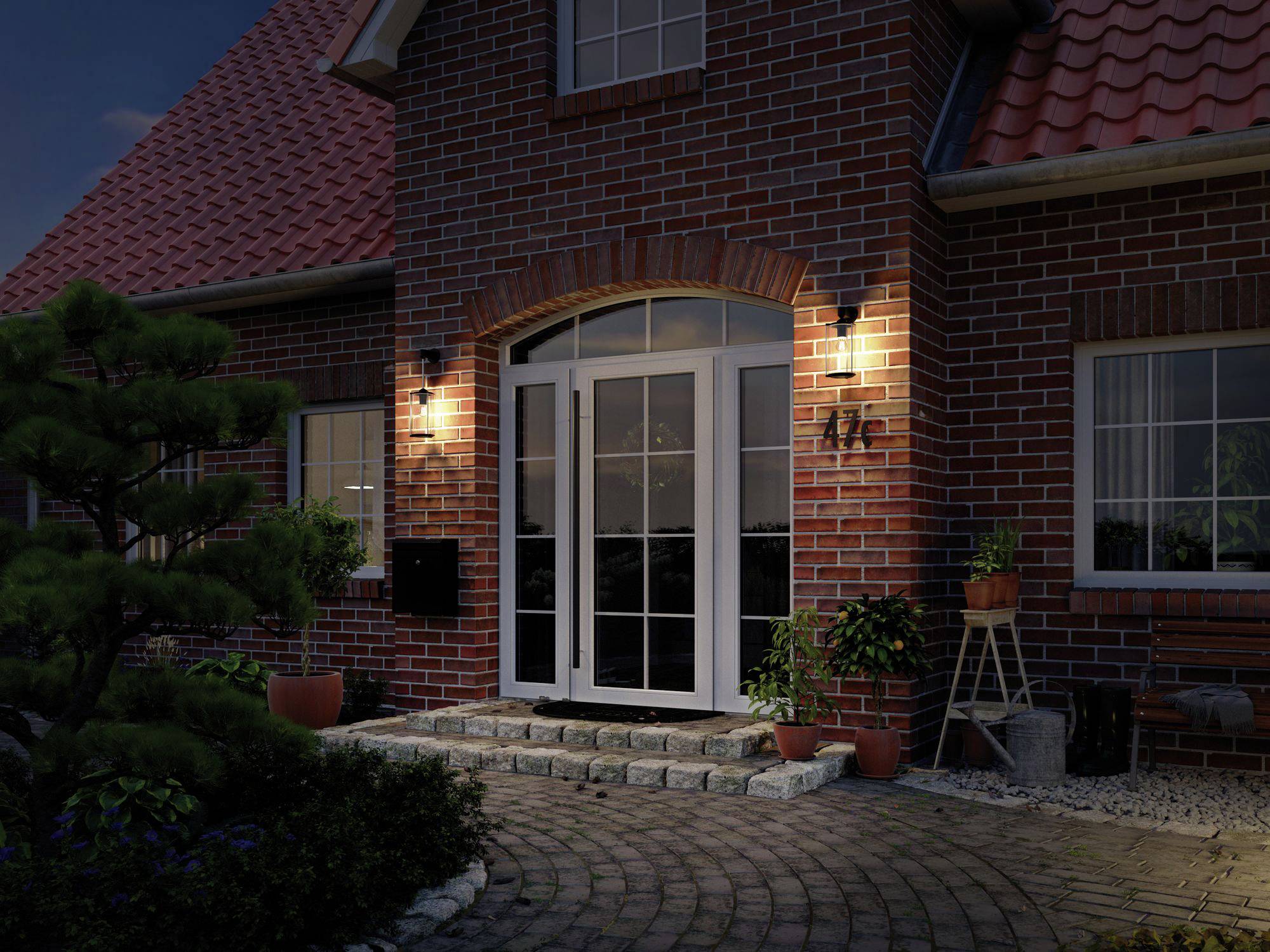 Bakstenen huis 's nachts, verlichte ingang met glazen deur en planten.