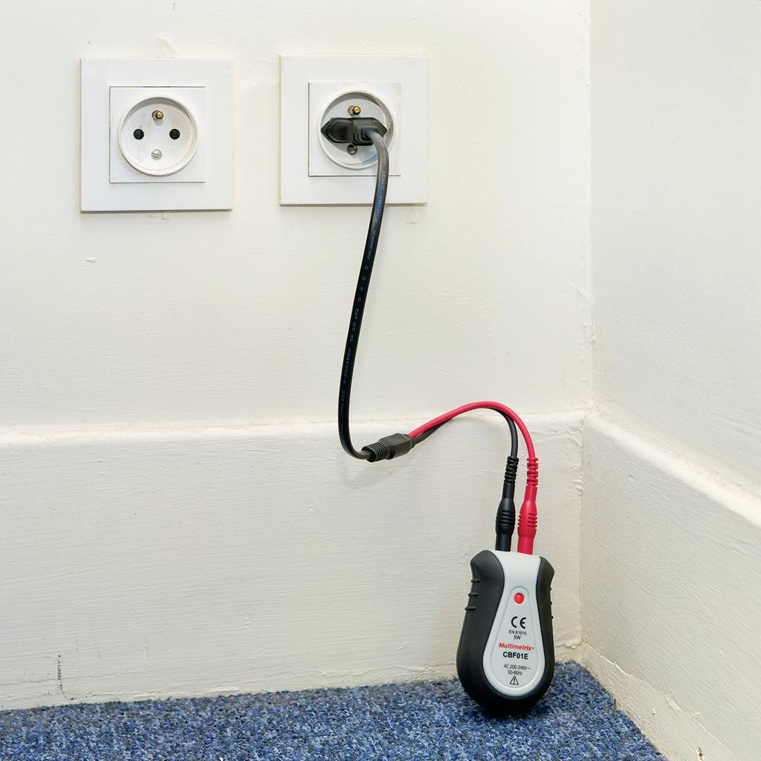 Een spanningzoeker is aangesloten op een stopcontact. Een ander kabel met stekker hangt los naast zich.