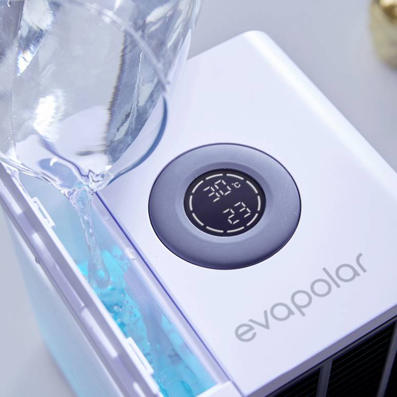 Een glas water wordt in een luchtvochtigheidsapparaat gegoten. Op het display van het apparaat wordt 30°C en 49% luchtvochtigheid weergegeven.