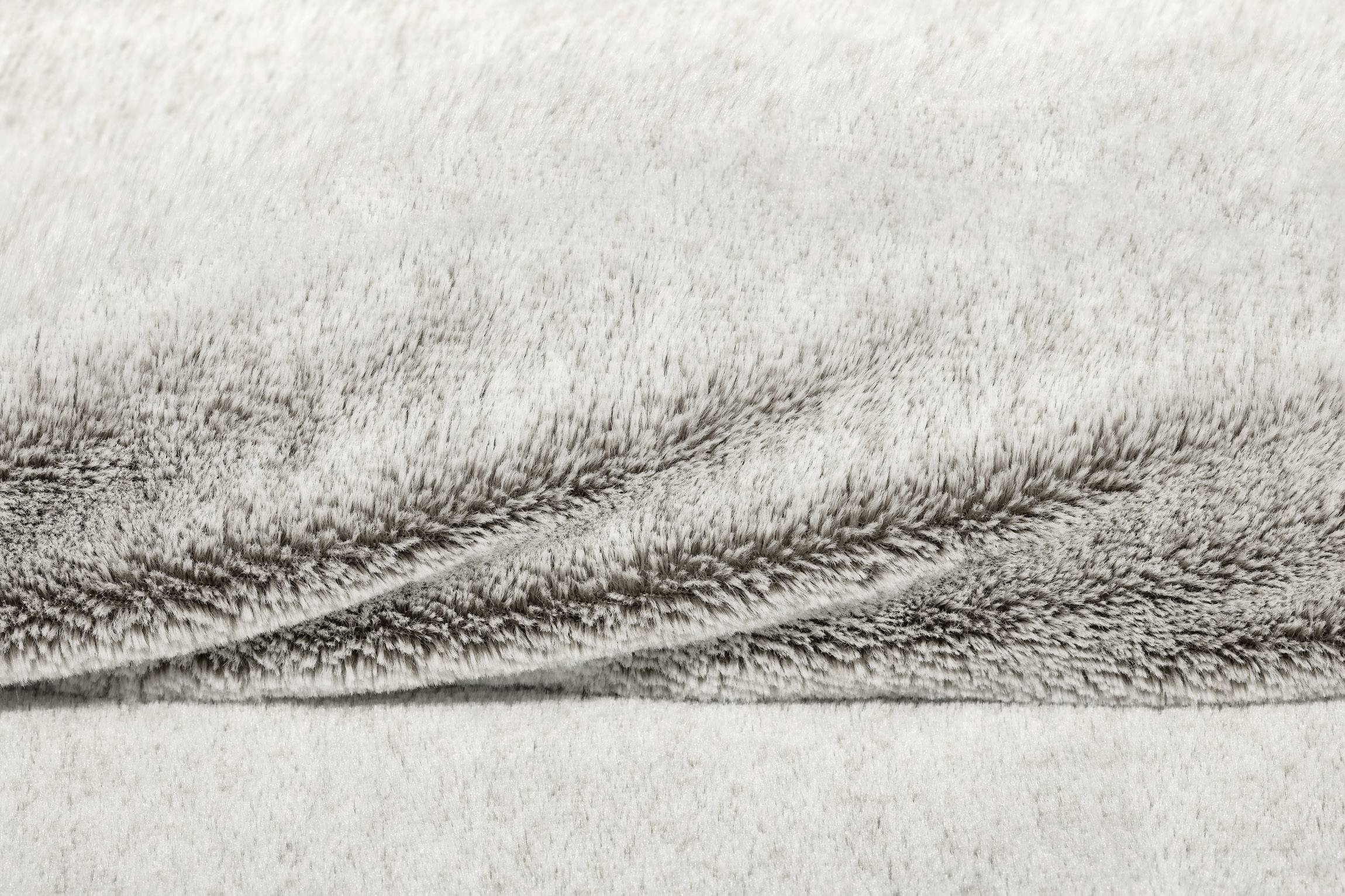 Een grijs, pluizig materiaal dat doet denken aan een deken of kledingstuk, vormt zachte golven en biedt een warme textuur.