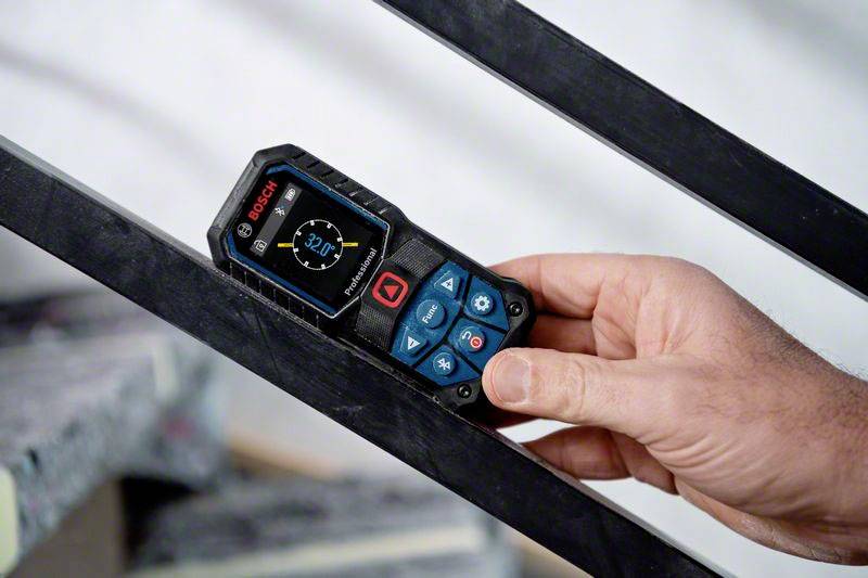 Een hand houdt een digitale Bosch-afstandsmeter vast die op een schuine metalen oppervlakte ligt. Het display toont '2,27m'.