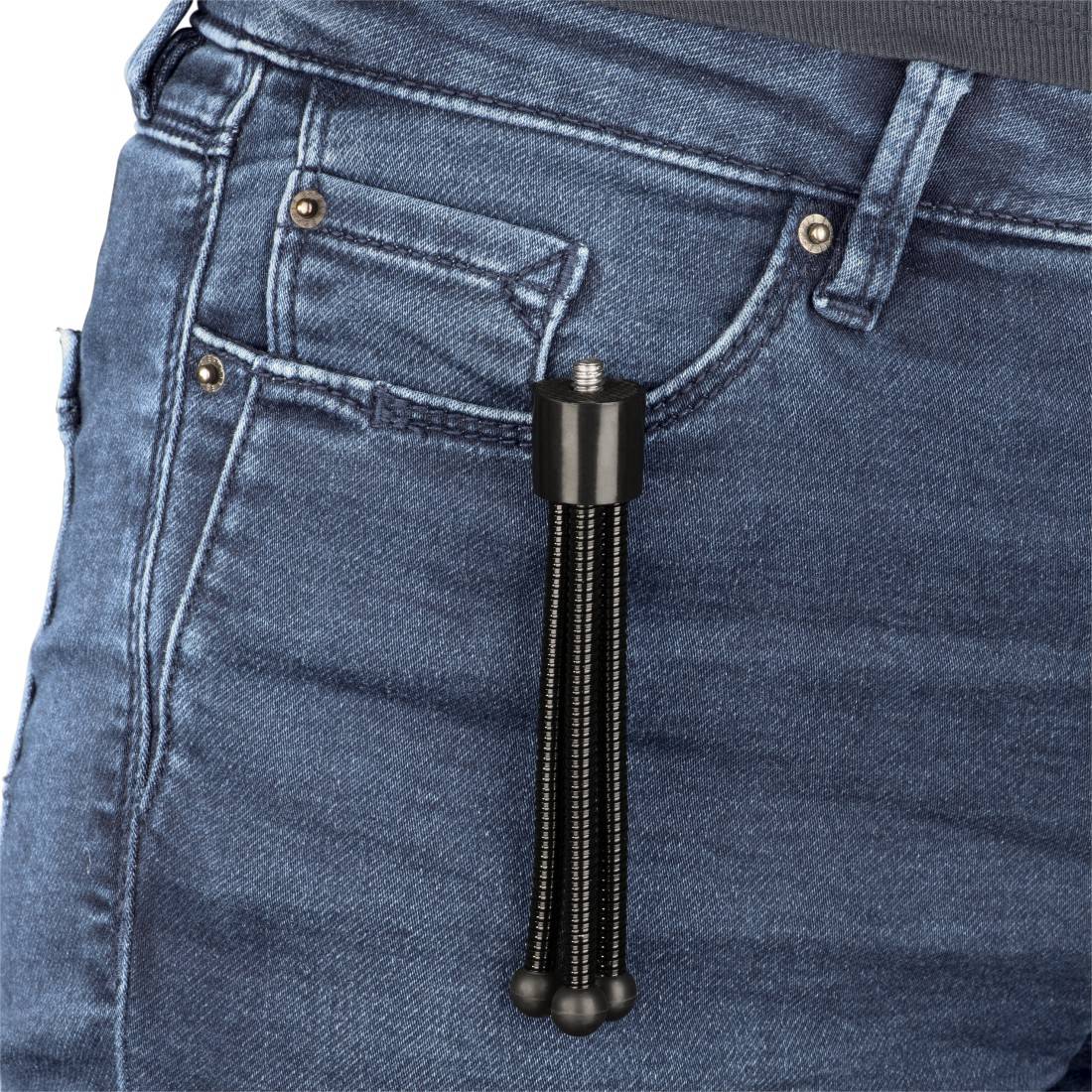 Een zwarte metalen franjeaanhanger die bevestigd is aan de broekriem van een blauwe spijkerbroek.