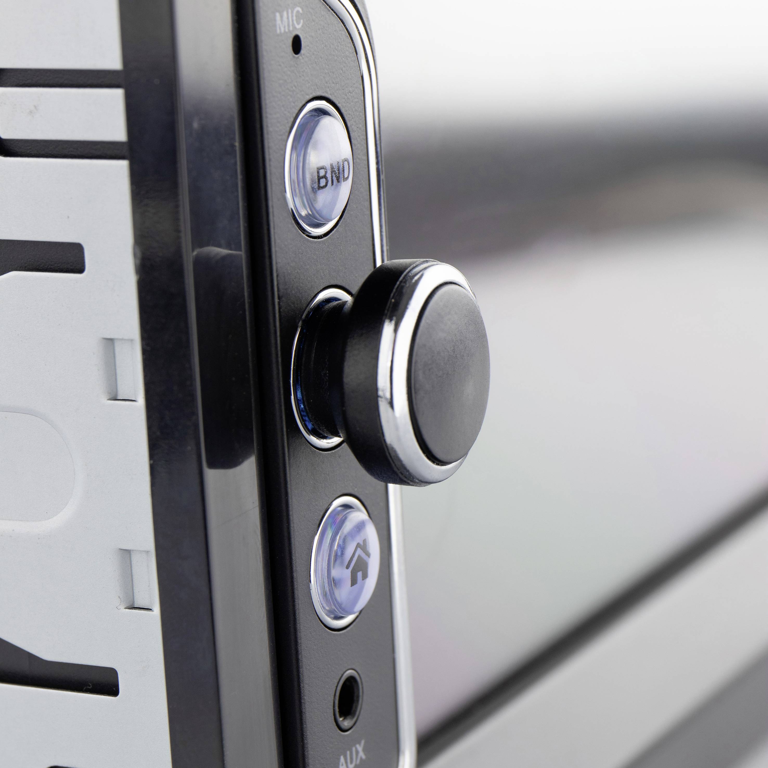 Close-up van een metalen knop op een elektronisch apparaat. Links zijn sleuven en een aansluiting zichtbaar.