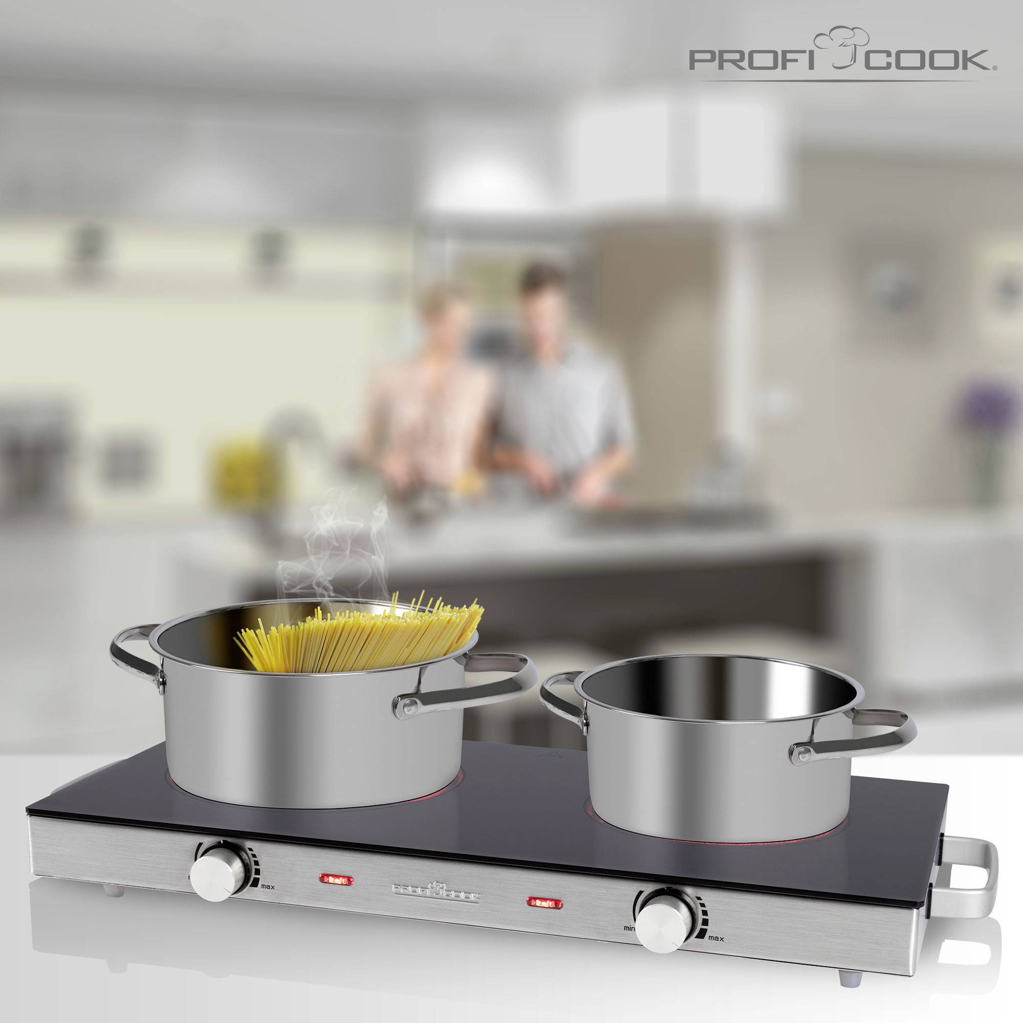 Twee potten op een fornuis, op de voorgrond met kokende spaghetti. Een onscherpe achtergrond toont twee personen in een keuken.