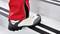 Persoon met rode broek beklimt een trap. Focus op witte sportschoen.
