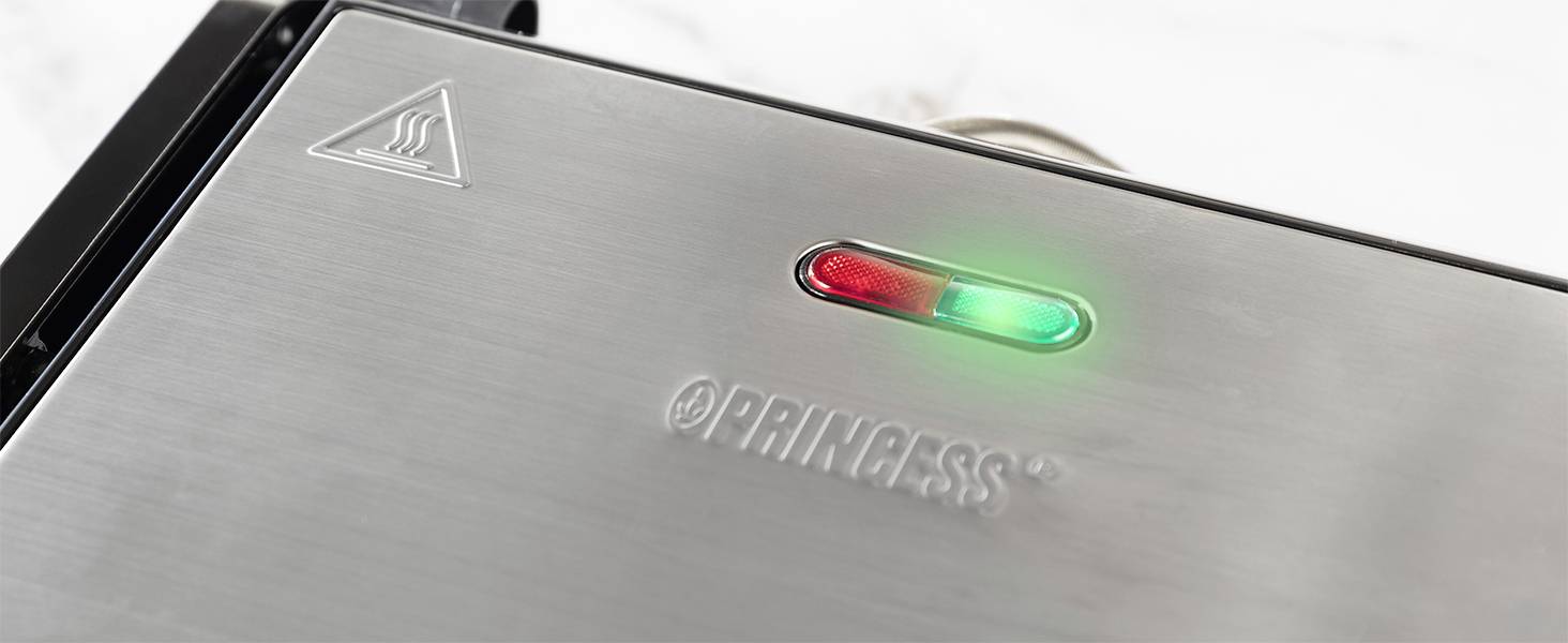 Close-up van een roestvrijstalen keukenmachine met een rood en groen indicatielampje. Het logo 'PRINCESS' is zichtbaar.
