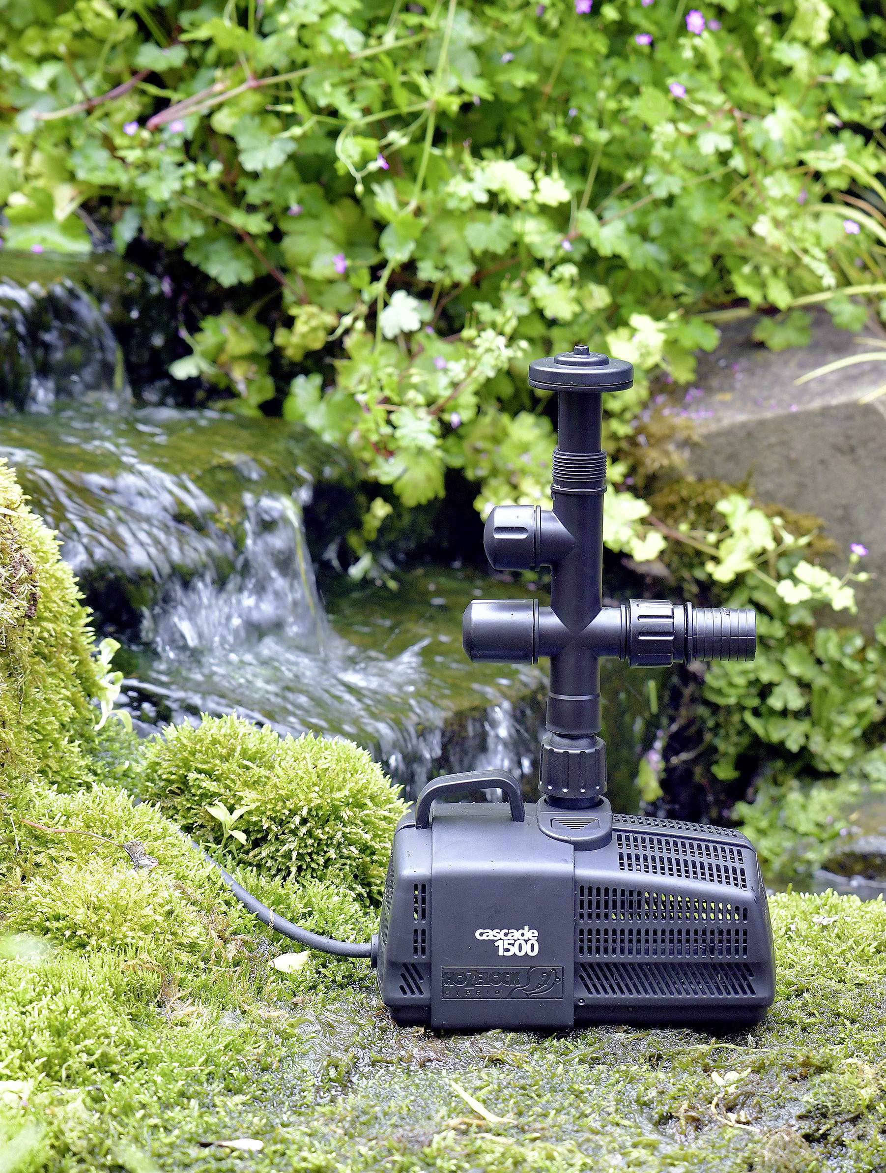 Een vijverpomp staat voor een kleine waterval, omringd door mos en groene vegetatie. Op de pomp staat de tekst 'Cascade 1500'.