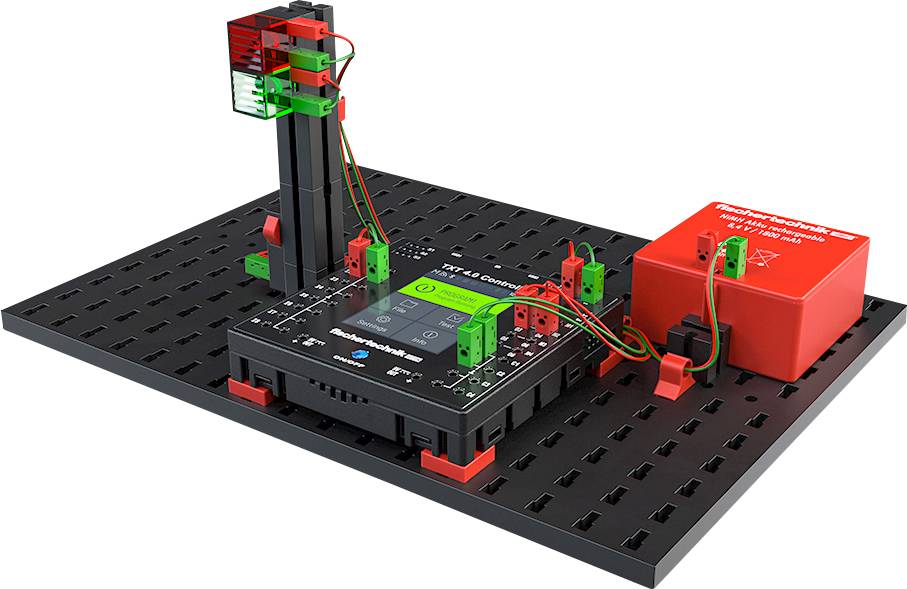 'STEM Lab'-bouwpakket op een zwart bord met rode en groene componenten en bekabeling. Hoofdmodule in het midden toont een scherm.