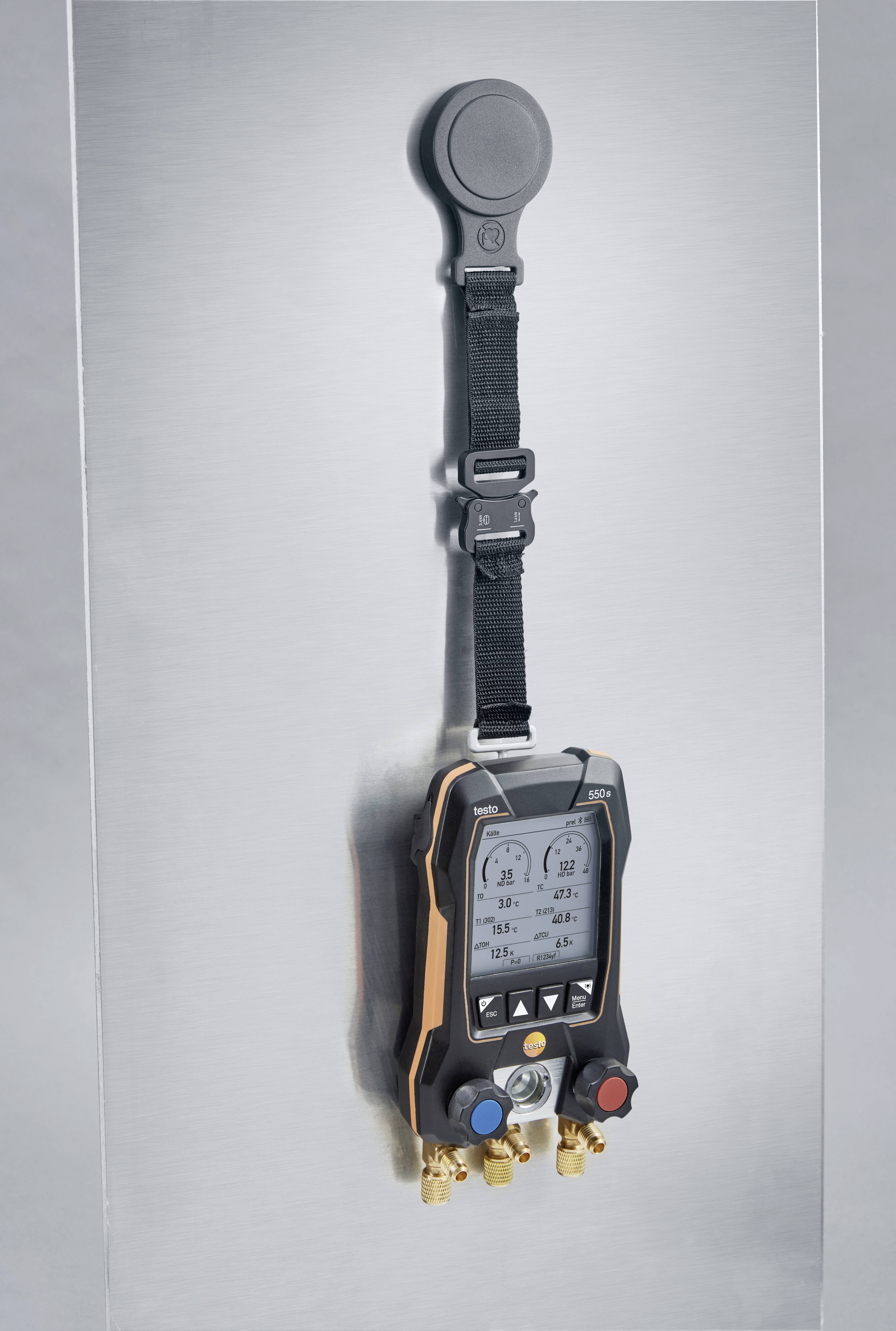 Digitaal meetinstrument aan een metalen muur opgehangen, toont druk- en temperatuurwaarden voor HVAC-systeemdiagnose.