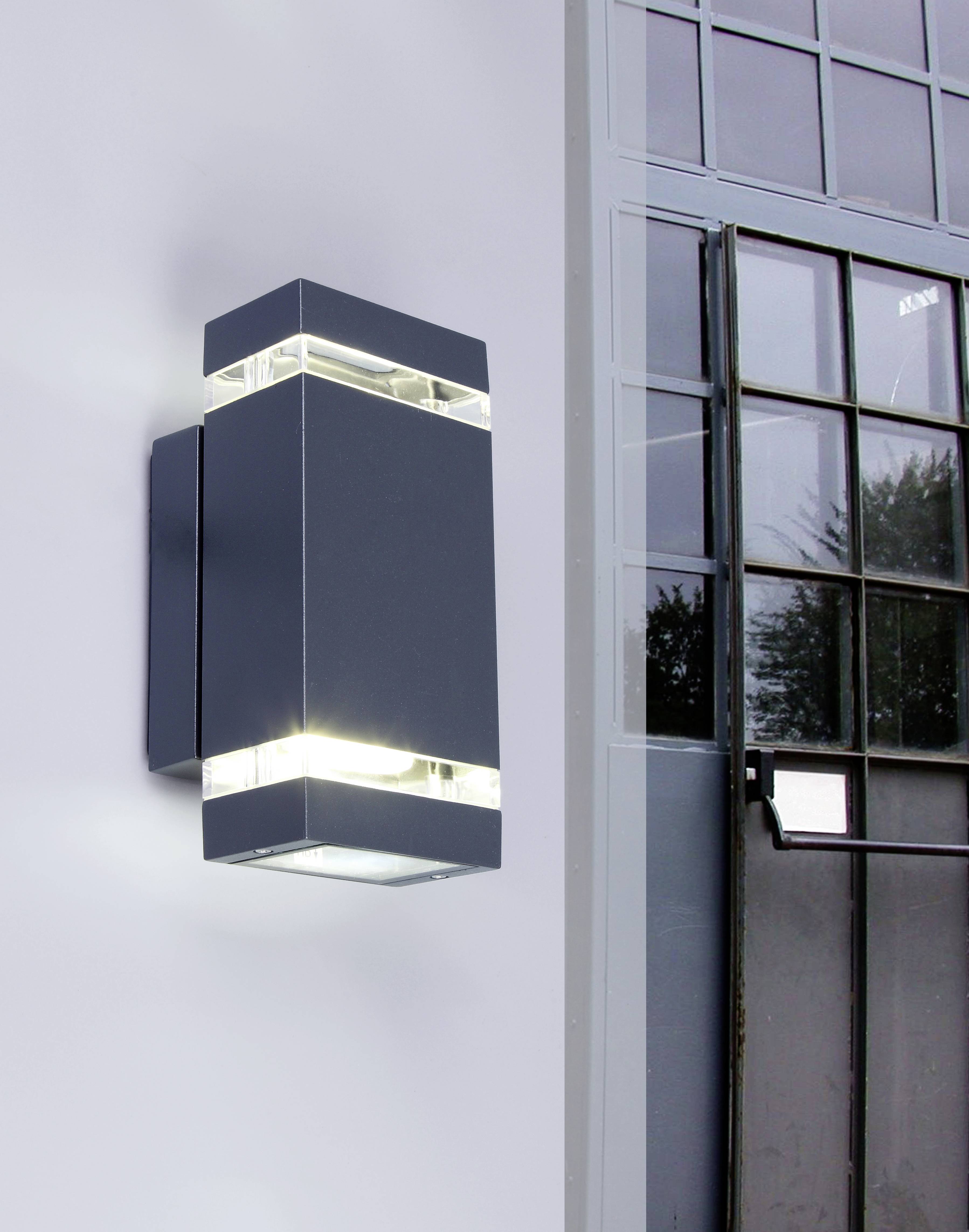 Zwarte, rechthoekige buitenlamp met glazen details aan een grijze muur naast een groot raam met metalen frame.