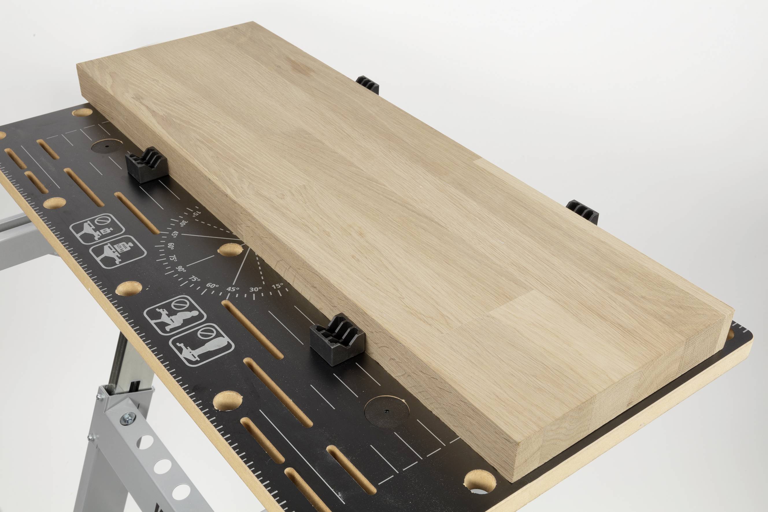 Houten plaat op een werktafel met lijmklemmen, omringd door markeringen en schalen voor uitlijning en meting.