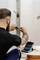 Een persoon werkt aan een metalen frame met gereedschappen. Een open gereedschapskist met schroeven staat op een tafel in de buurt.
