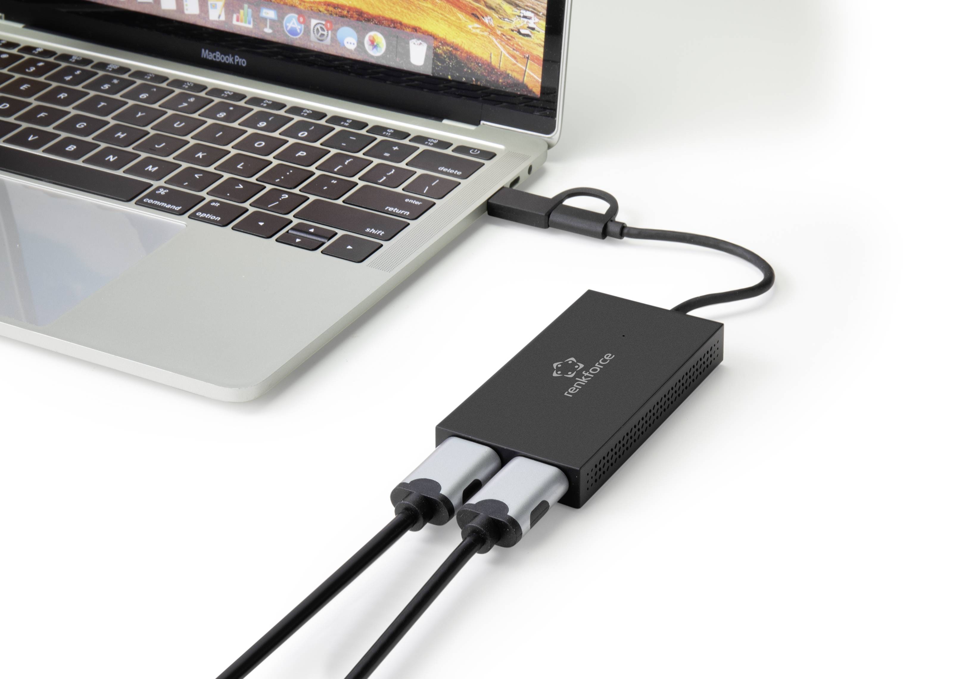 Een laptop is verbonden met een zwarte adapter die twee kabels aansluit. De adapter vergemakkelijkt de aansluiting van externe apparaten.