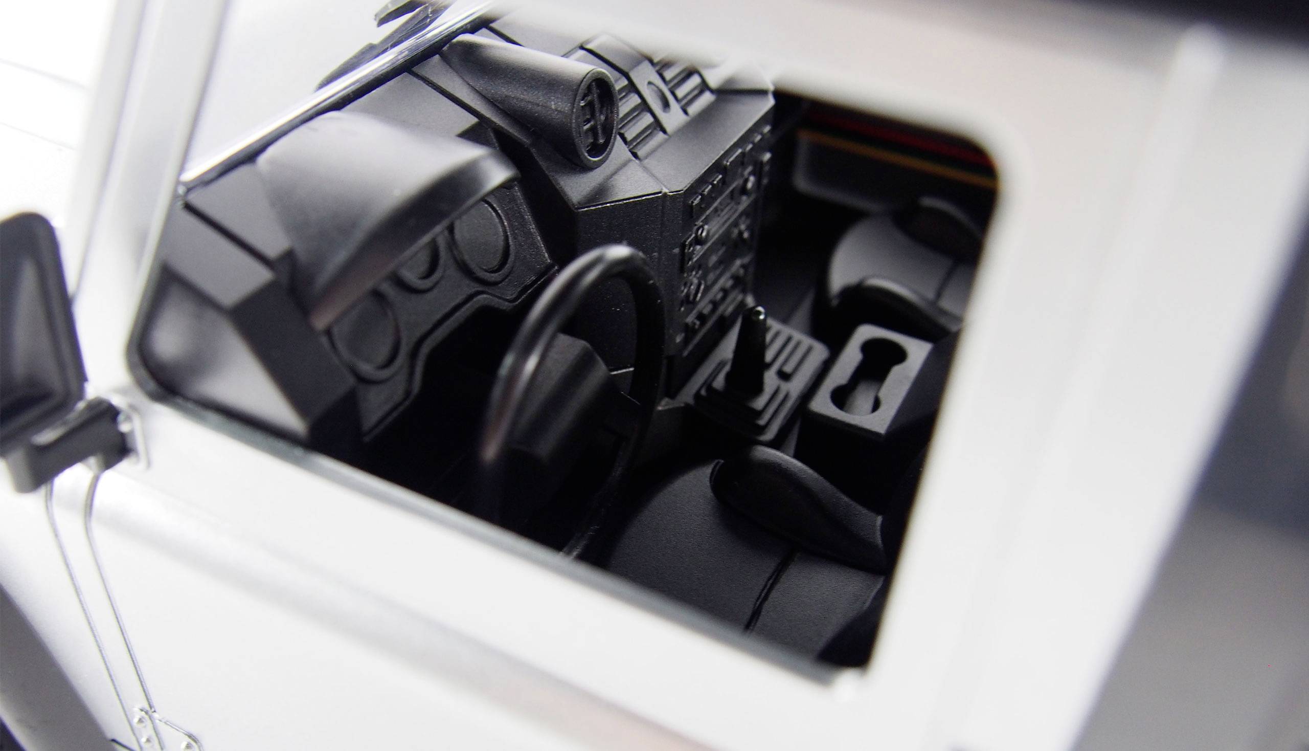 Binnenaanzicht van een modelauto, toont het dashboard met stuurwiel, instrumenten en middenconsole.