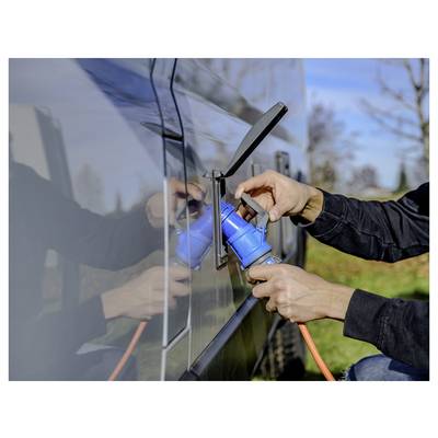 Persoon die een blauwe stroomkabel in de laadpoort van een elektrisch voertuig buiten aansluiten.