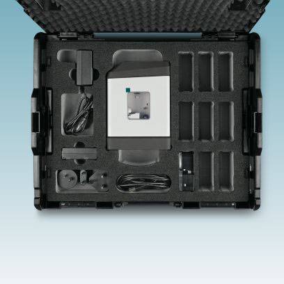 Zwarte transportkoffer met een wit apparaat in het midden en meerdere vakken voor toebehoren, op blauwe achtergrond.