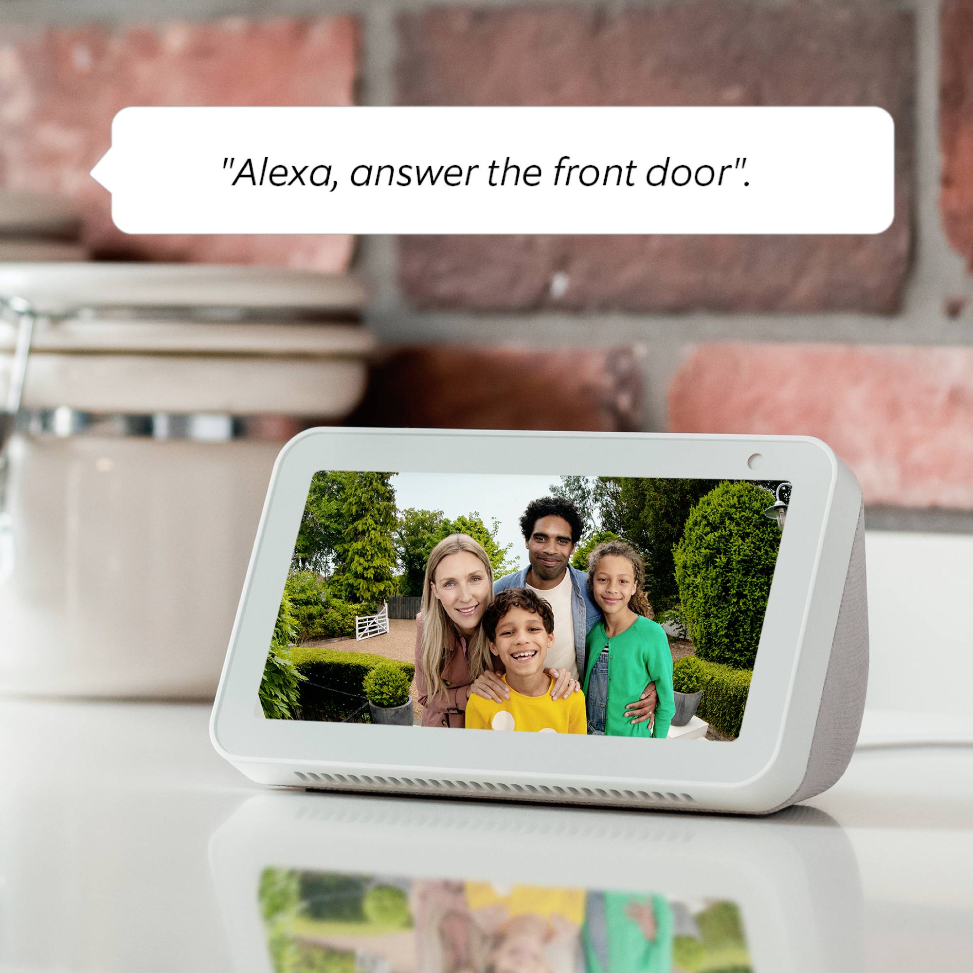 Een intelligent scherm toont een familiefoto. Tekst op de afbeelding: 'Alexa, open de voordeur'.