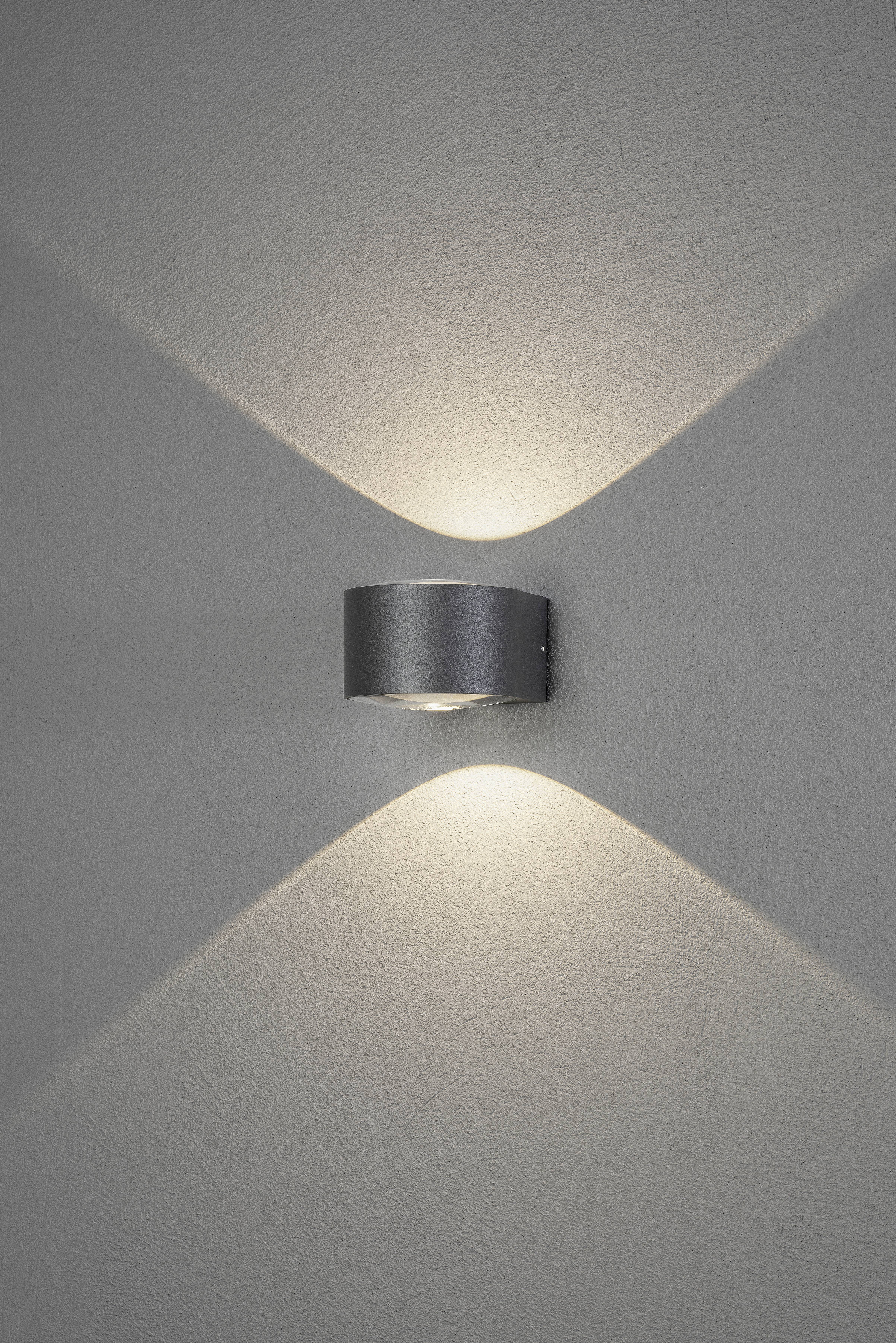 Wandlamp werpt lichtstralen in X-vorm tegen de muur en creëert een decoratief, zacht lichtspel.