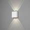 Witte, vierkante wandlamp straalt warm licht naar boven en beneden op grijze muur, creëert V-patroon.