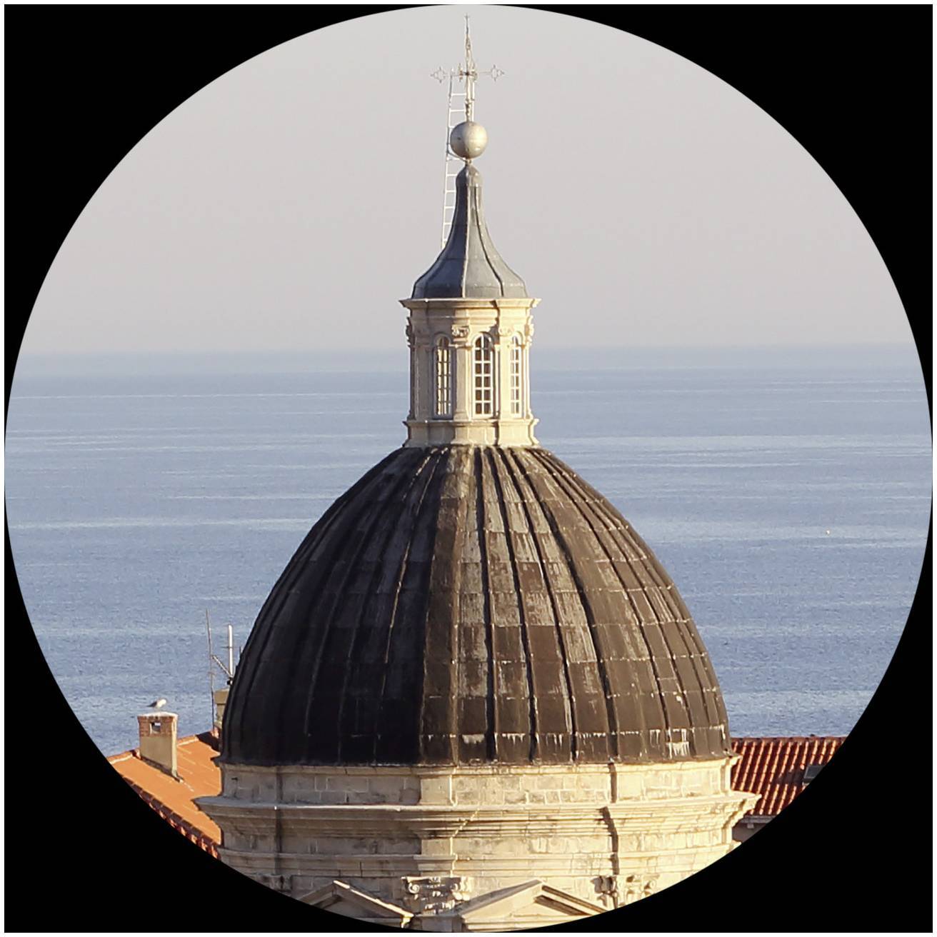 Koepel van een historisch gebouw voor een heldere blauwe horizon van de zee, gefotografeerd vanuit een verhoogd perspectief.