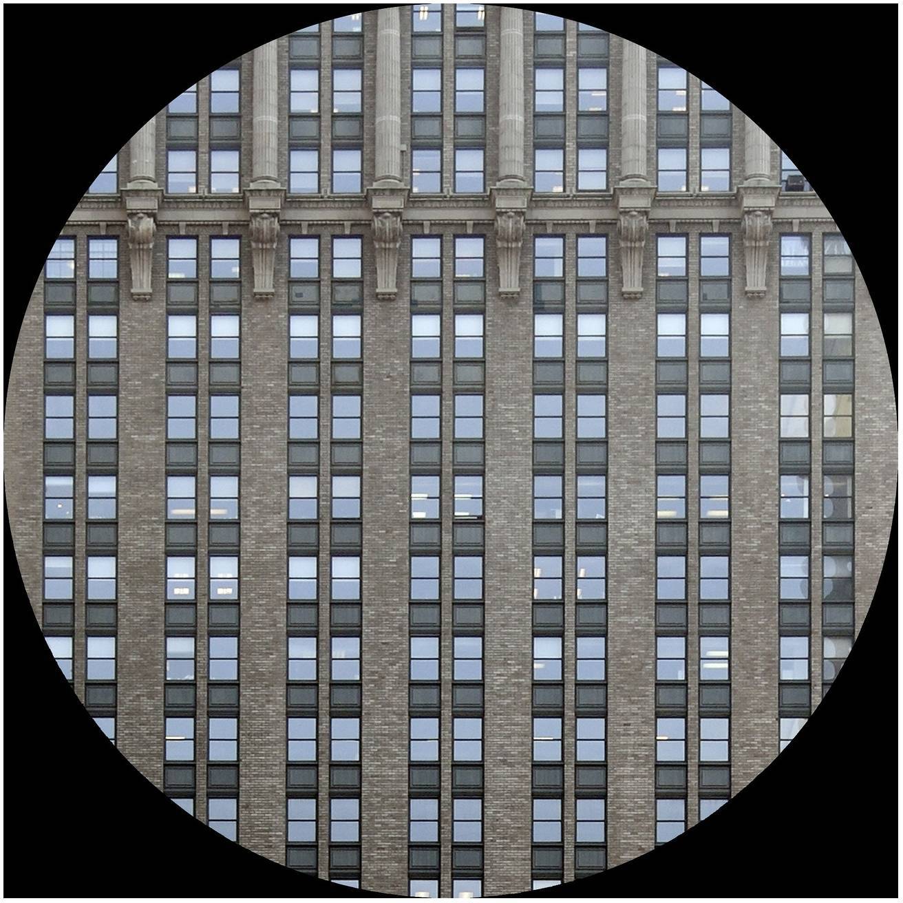 Een historisch hooggebouw met een bakstenen gevel en regelmatige rijen ramen in een cilindrische omlijsting.