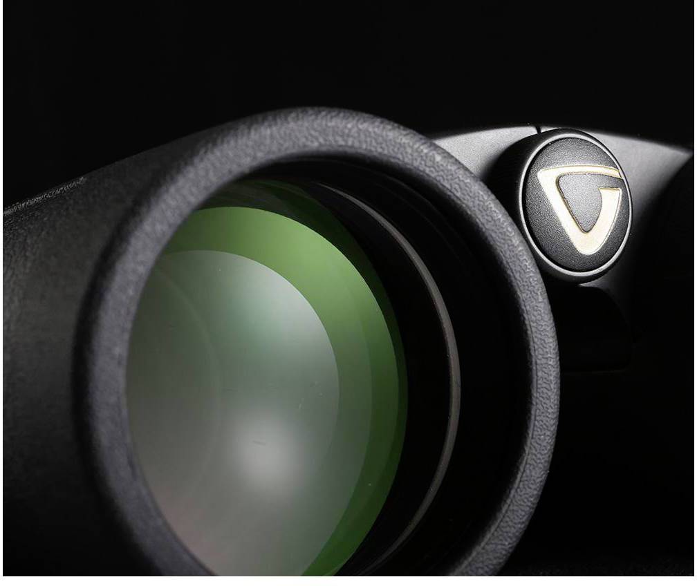 Een verrekijker-oculair close-up tegen een zwarte achtergrond. Links een groen glas, rechts een scherpstelwiel.