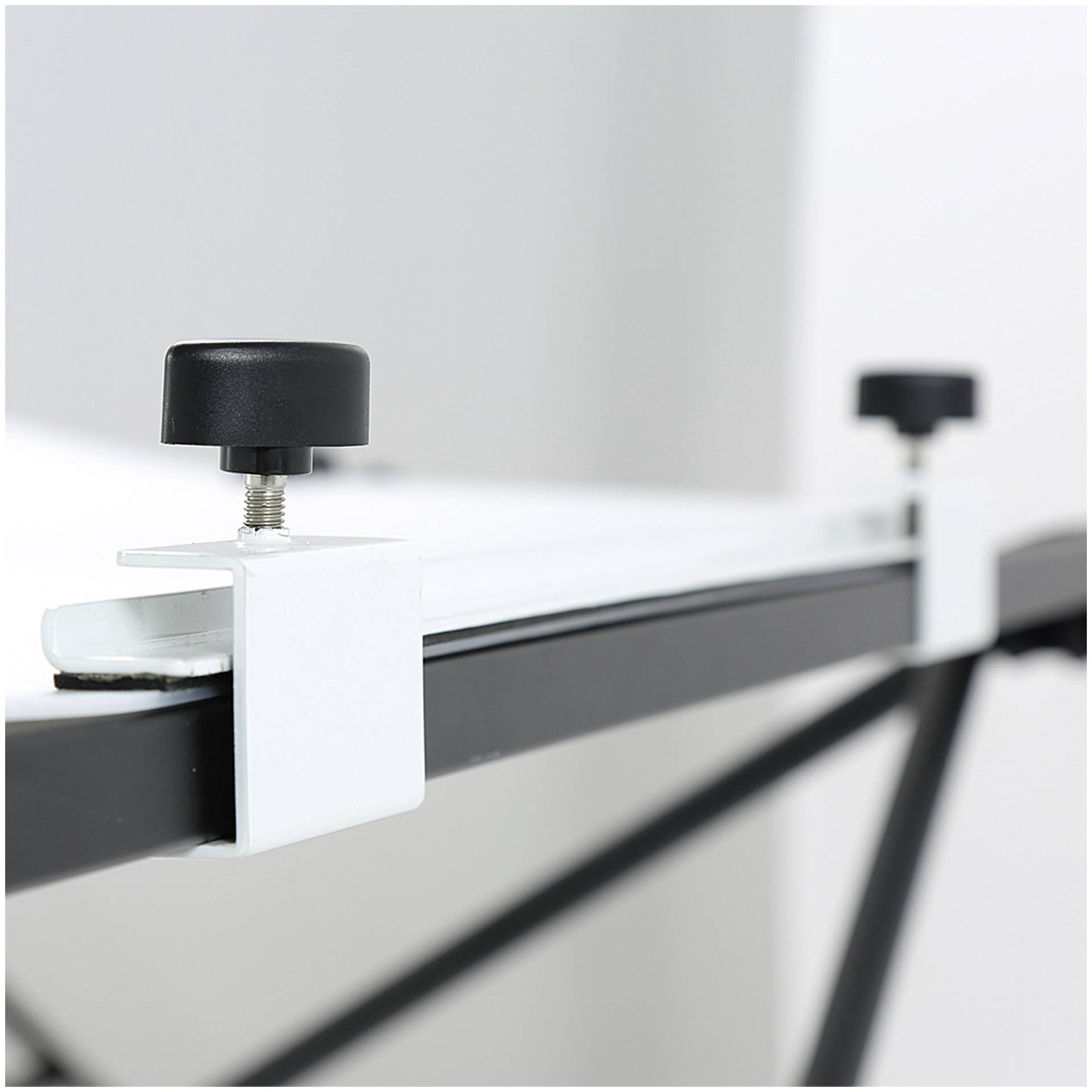 Verstelbare tafelpoot met zwarte draaiknop, gemonteerd op een witte plaat.