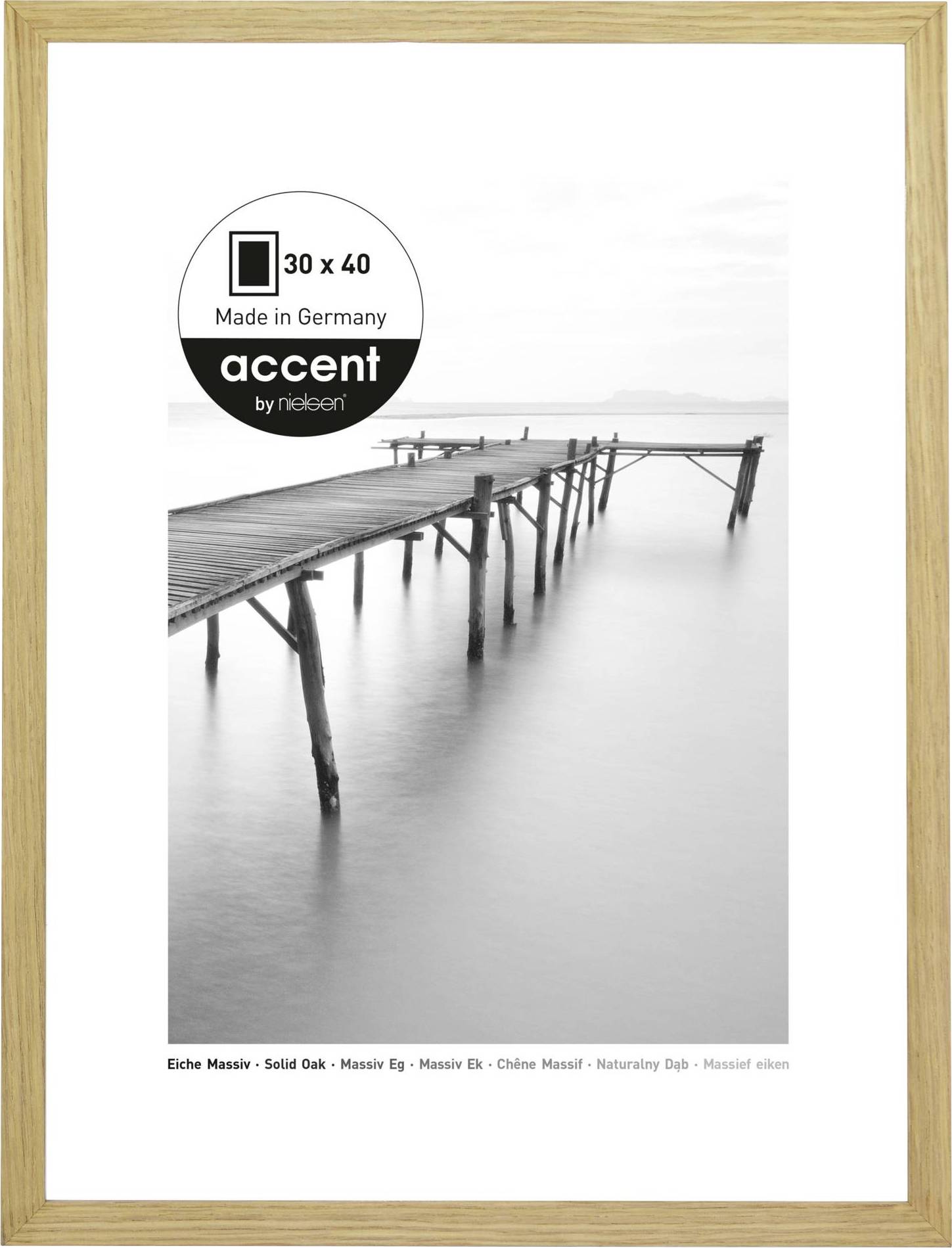 Zwart-wit foto van een lange houten steiger die uitsteekt in de kalme zee. Rechthoekig frame met etiket 'Made in Germany' linksboven.