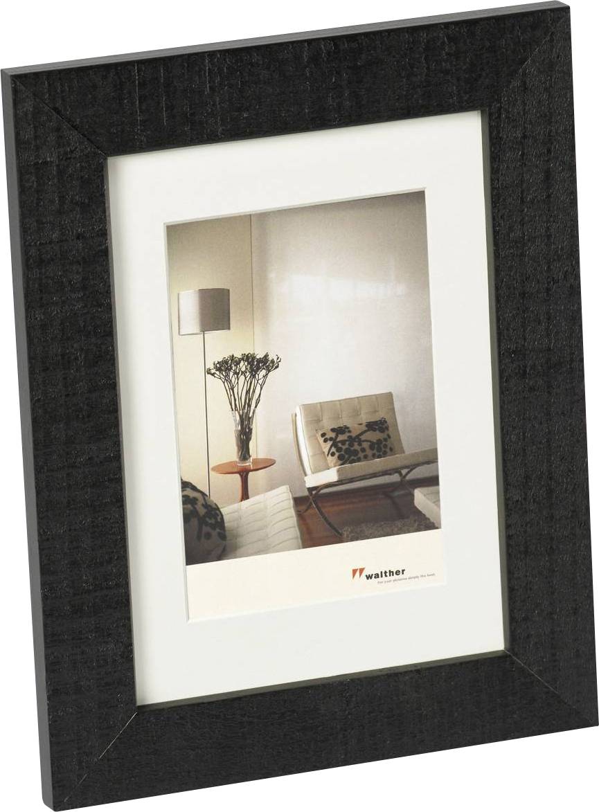 Zwarte fotolijst met een foto van een modern ingericht woonkamerinterieur met een stoel, een bijzettafel en een plant.