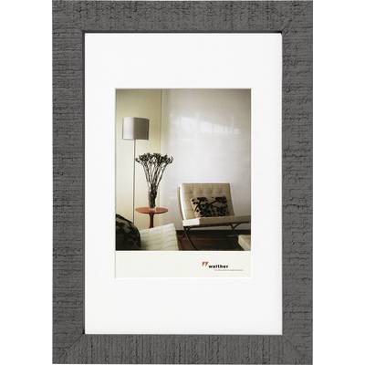 Een modern woonkamer met een designerstoel, een staande lamp en een tafel waarop een vaas met planten staat.