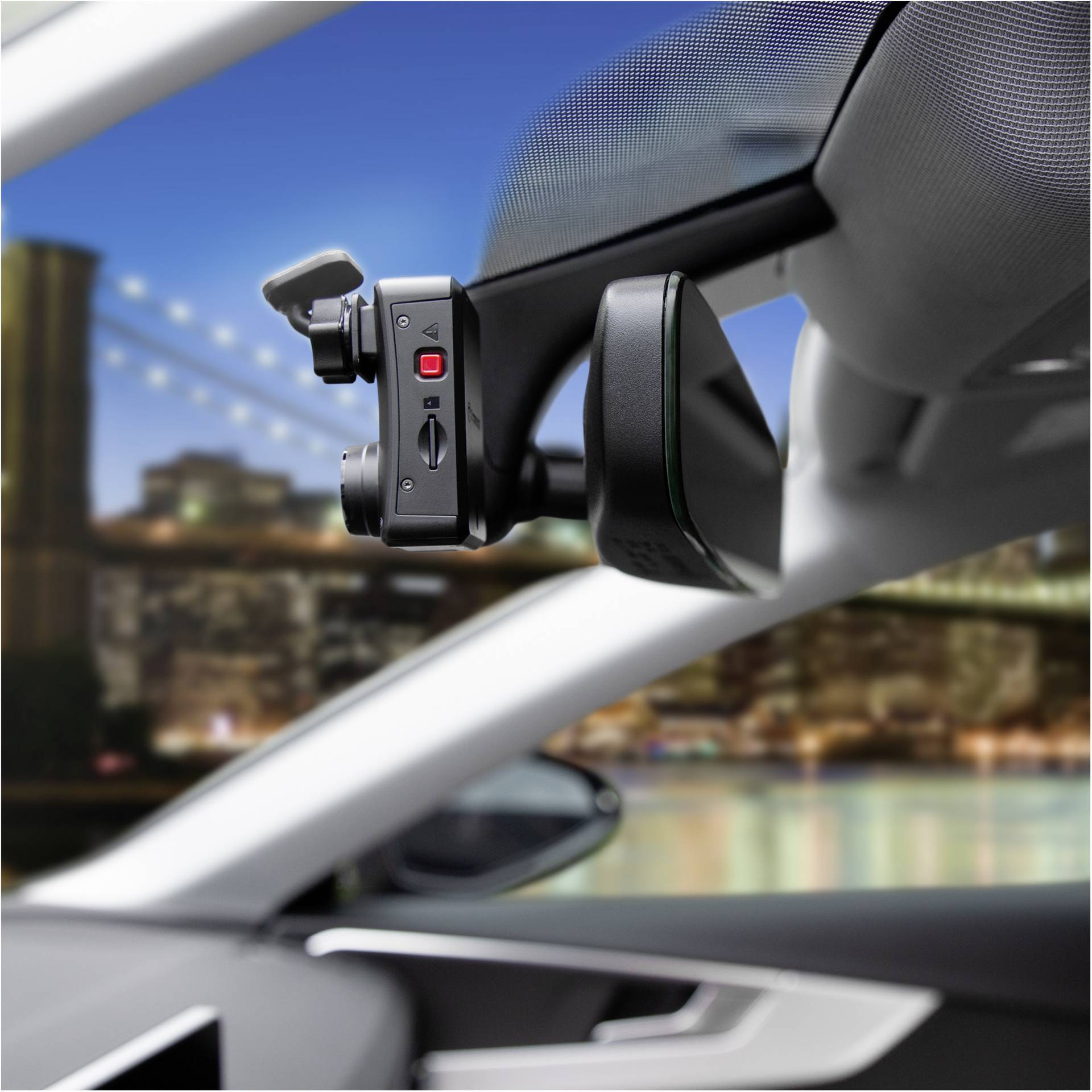 Interieur van een auto met een dashcam geïnstalleerd, wazig silhouet van een skyline op de achtergrond, toont stedelijke omgeving en bewakingstechnologie.