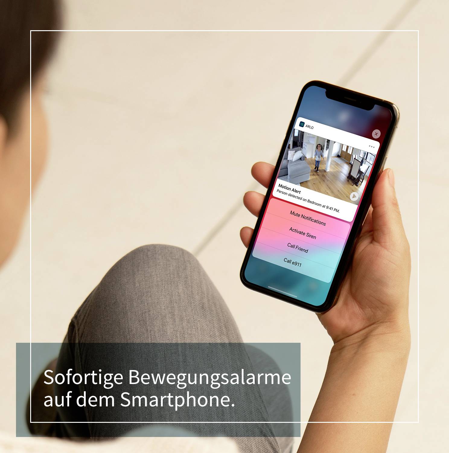 Een persoon houdt een smartphone vast waarop een beveiligingscamera-app met live-beeldweergave wordt getoond. Tekst: 'Direct bewegingsalarmen op uw smartphone.'