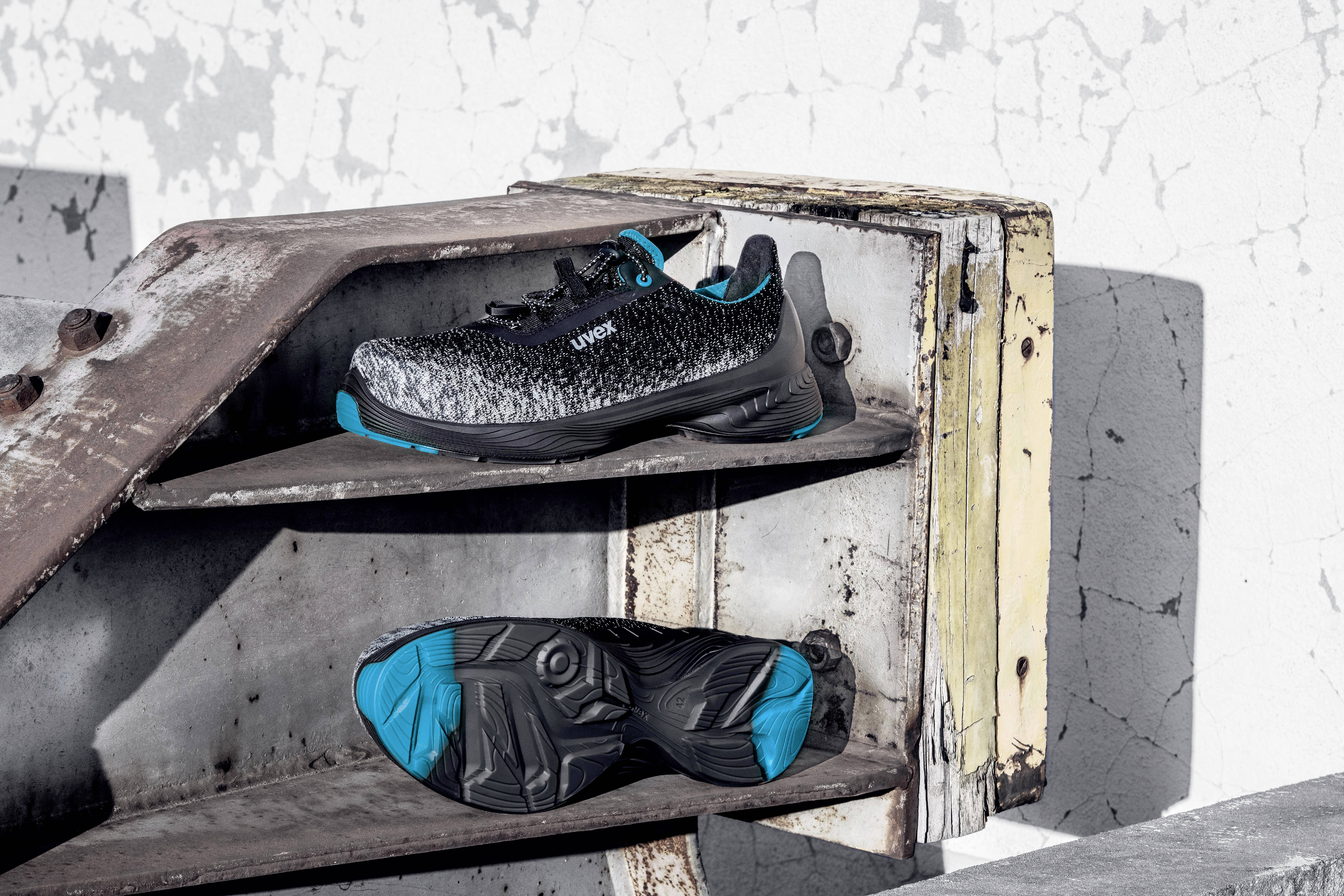 Sportschoenen in het zwart en blauw met anti-slip zool op een oud, roestig metalen rek voor een afbladderende muur.