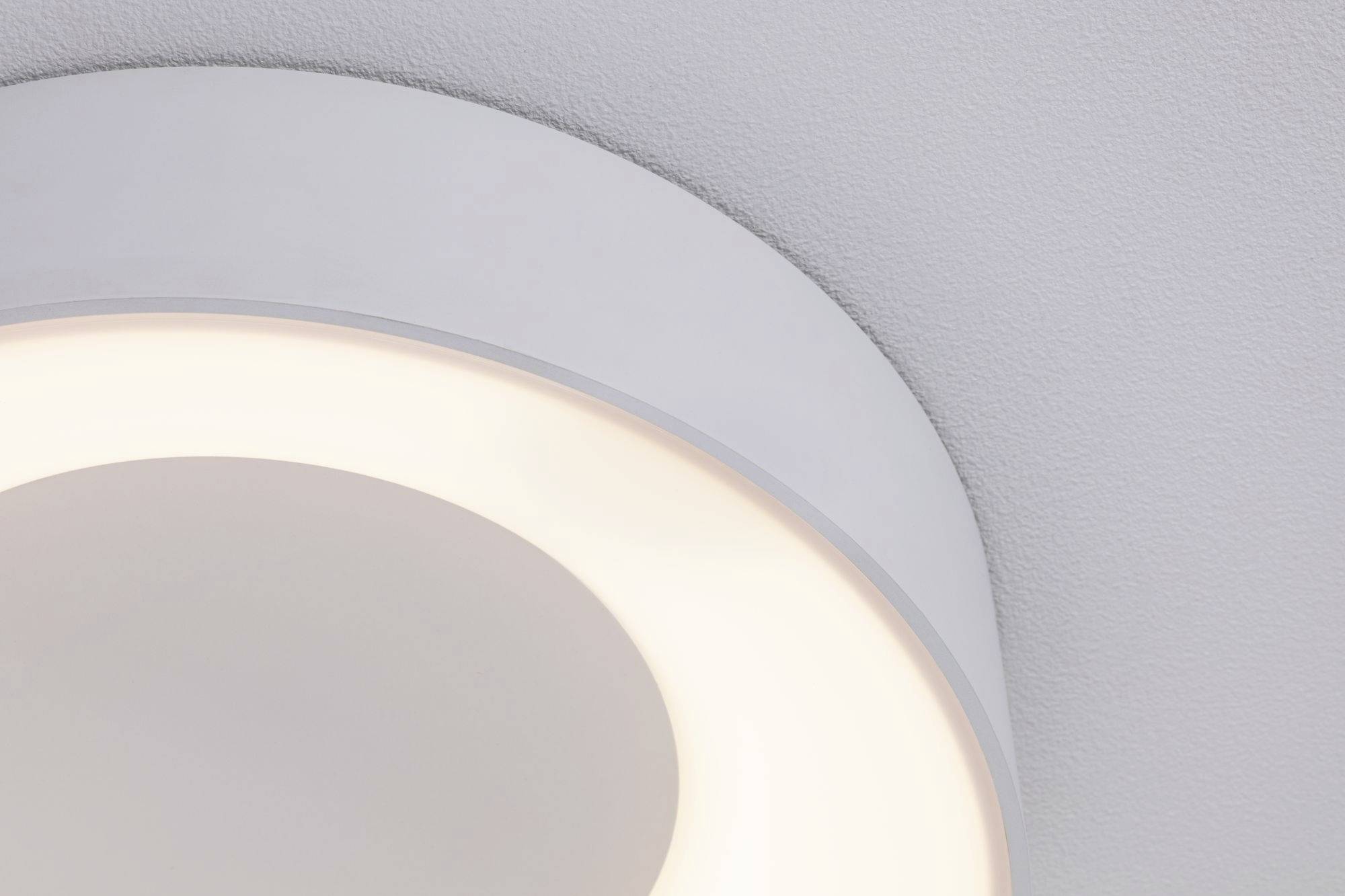 Een ronde, moderne plafondlamp straalt zacht, warm licht uit en is gemonteerd aan een grijze plafond.