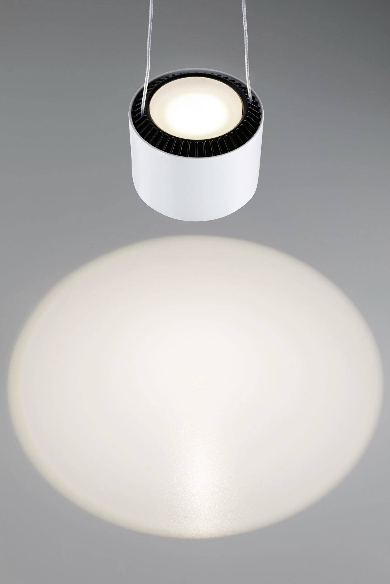 Een cilindrische plafondlamp straalt een cirkelvormig lichtpatroon op de vloer.
