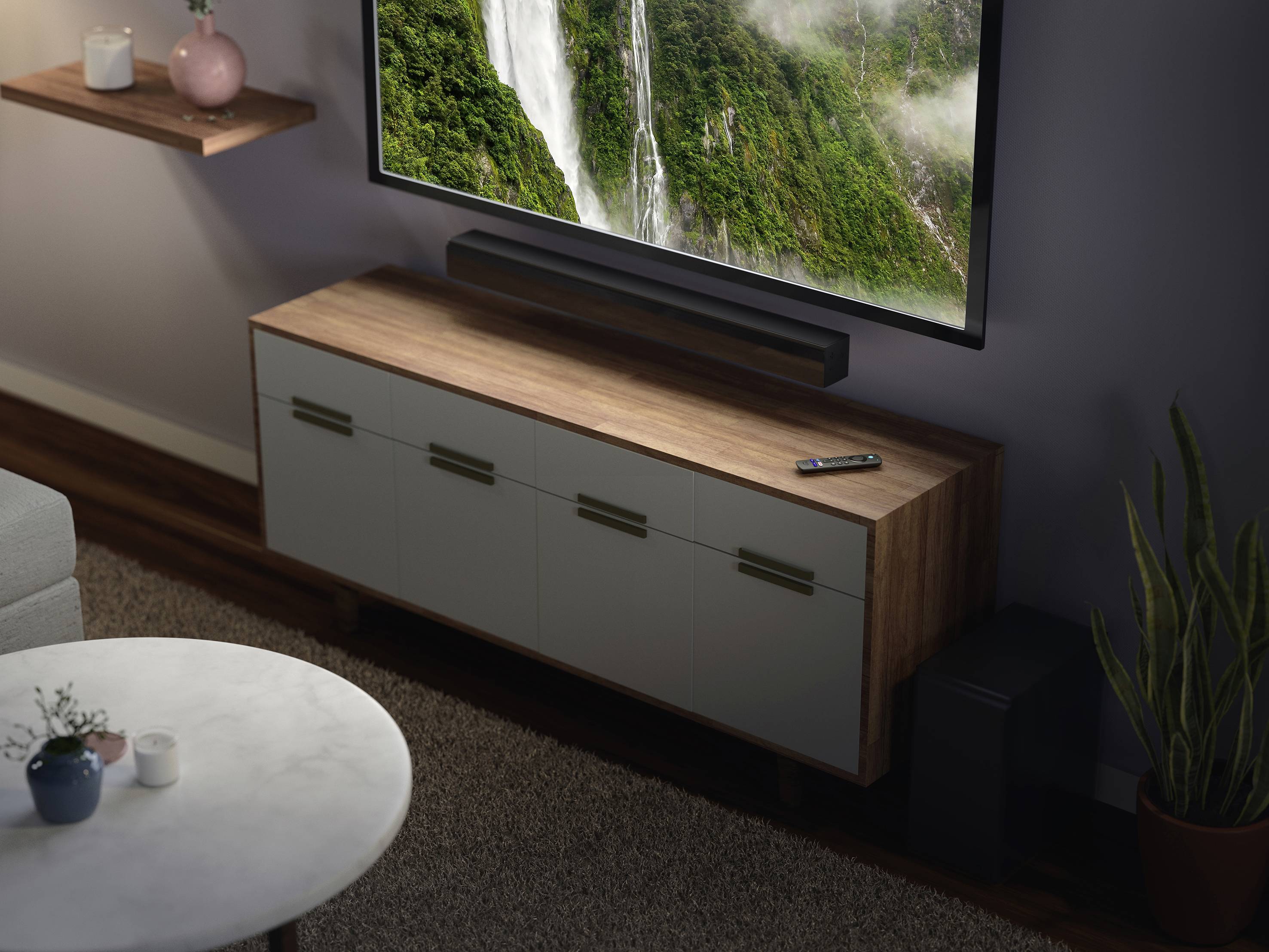 Een televisie vertoont een watervalscène. Hij staat op een houten meubel naast een tafel met planten en een luidspreker.