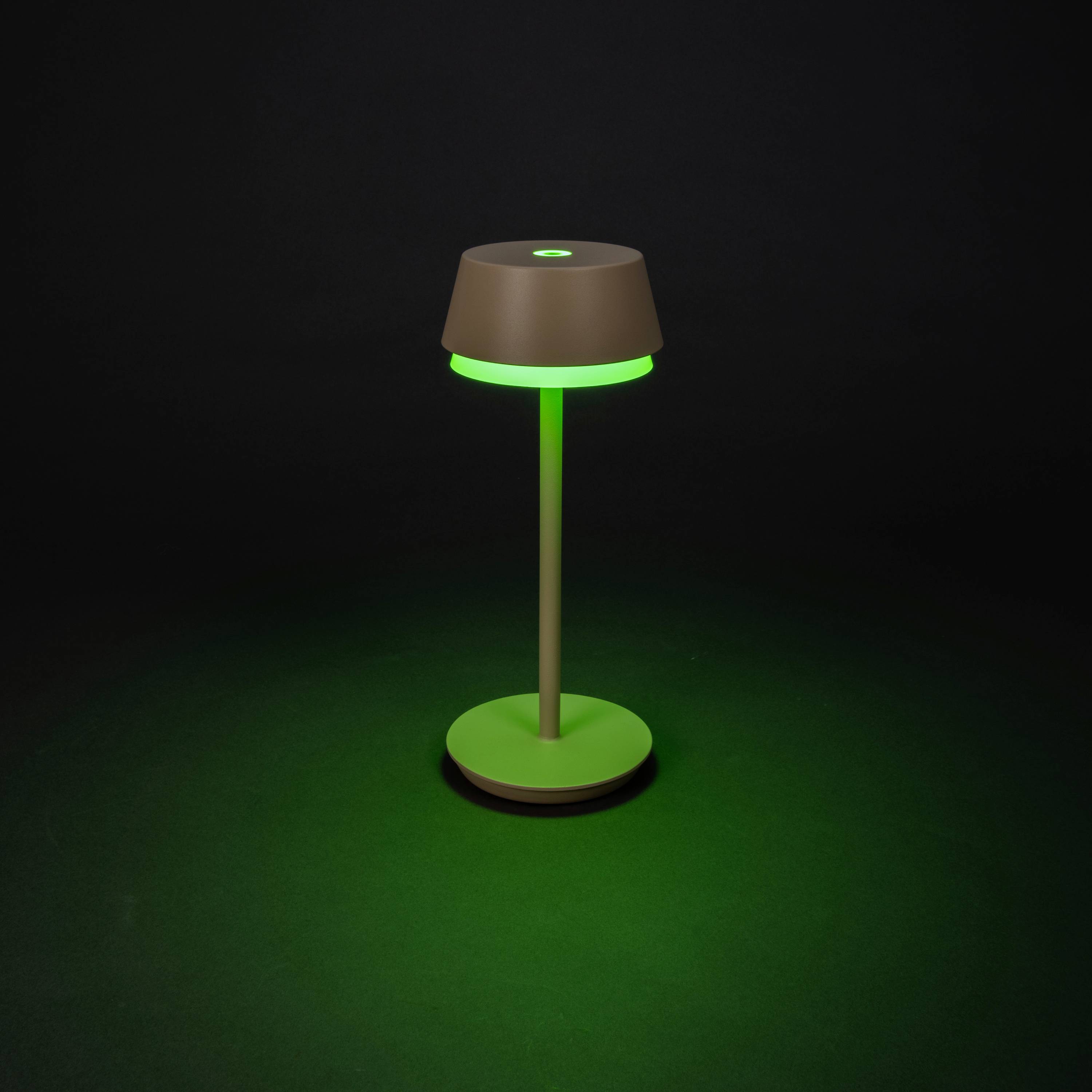 Een bruine tafellamp met groen licht staat voor een donkere achtergrond.